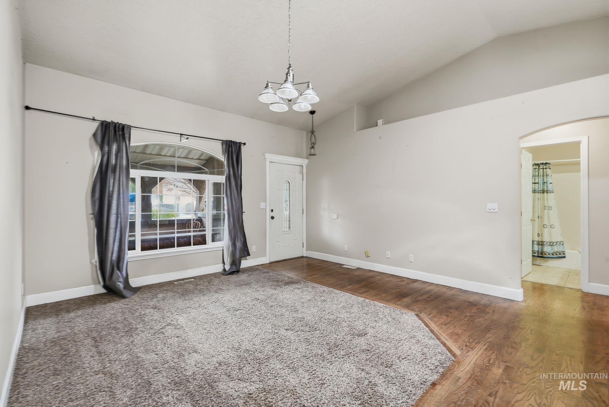Vaulted ceiling accentuates this carpeted and wood-finish flooring area