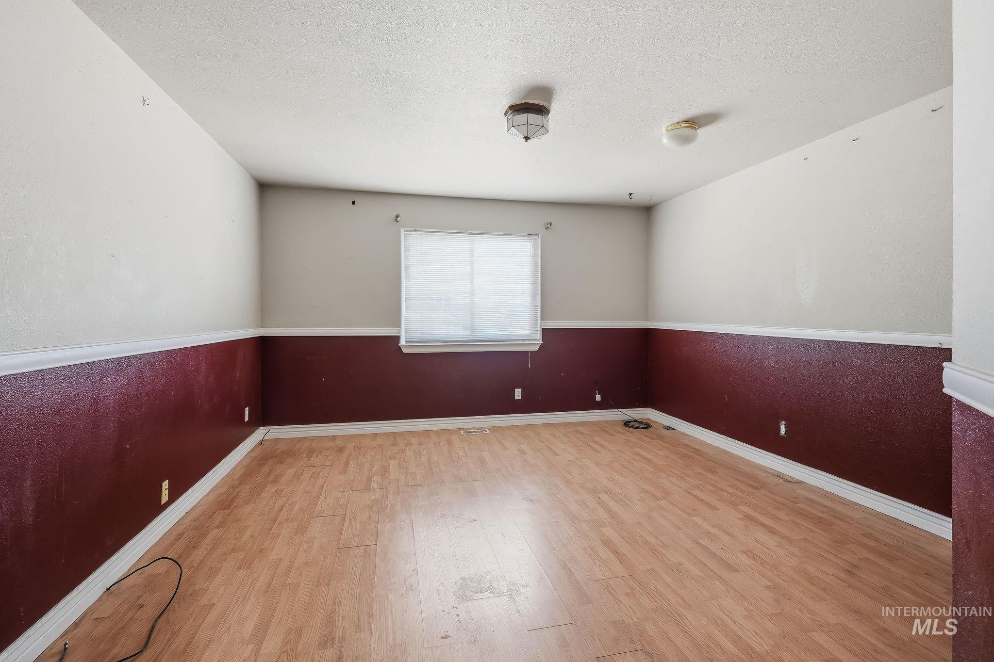 Room featuring wood-finish flooring, two-tone painted walls with a chair rail, and a window with blinds