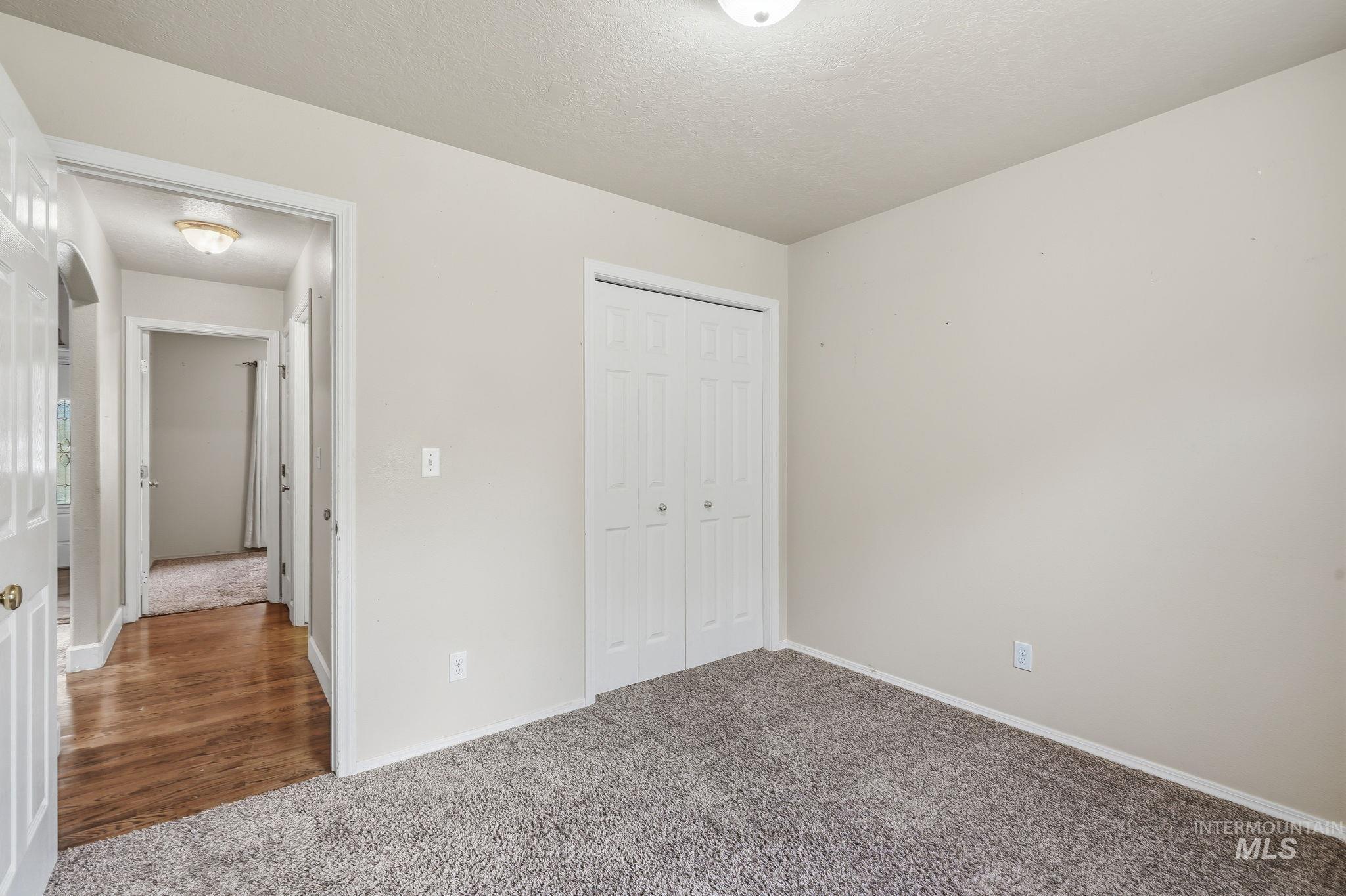 Room featuring gray textured carpeting, neutral wall finishes, and a bi-fold closet