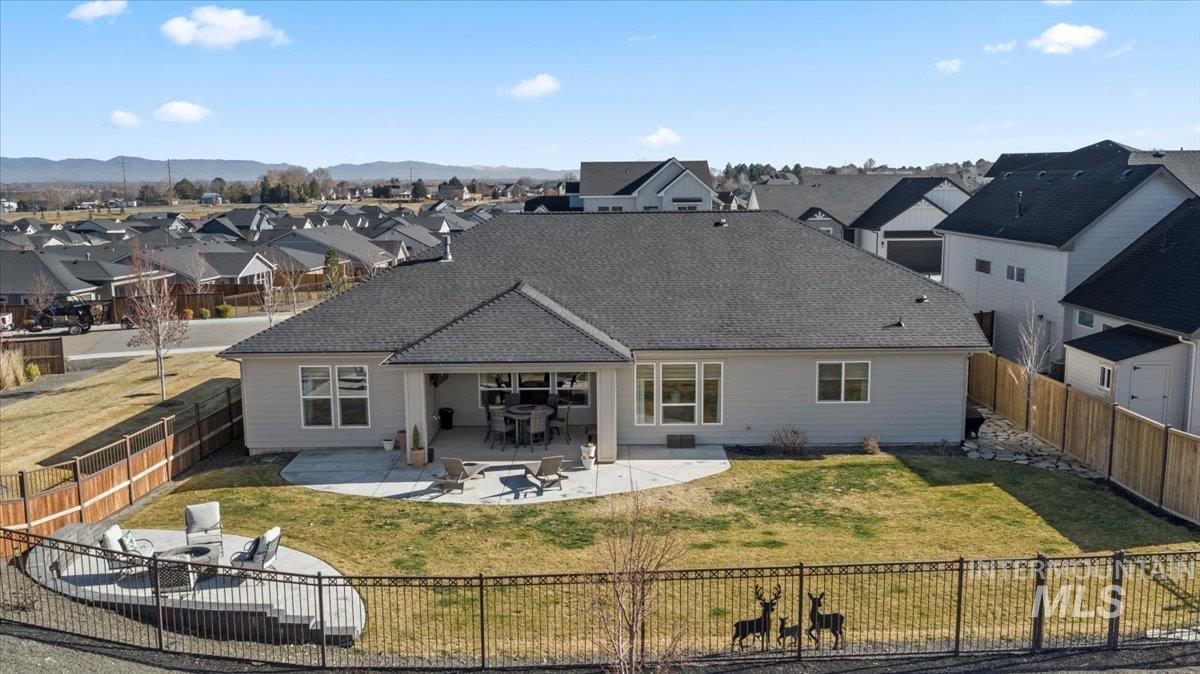Rear view of house featuring a residential view, a patio, a fenced backyard, and a shingled roof