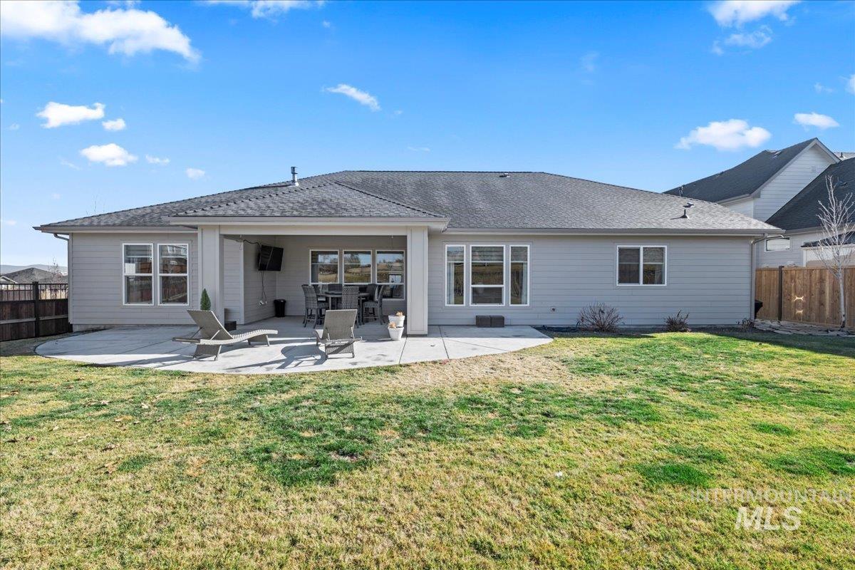 Back of house featuring a fenced backyard, a patio area, and a shingled roof