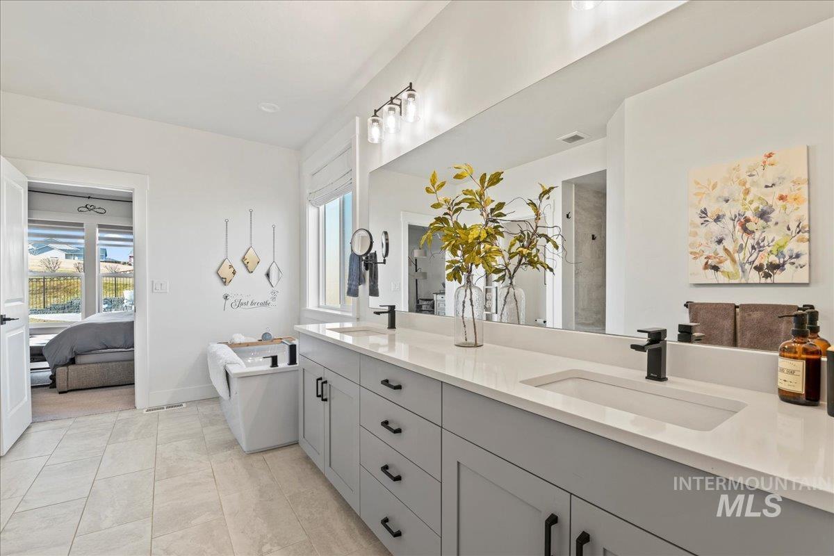 Bathroom with double vanity, a stall shower, connected bathroom, and a freestanding bath