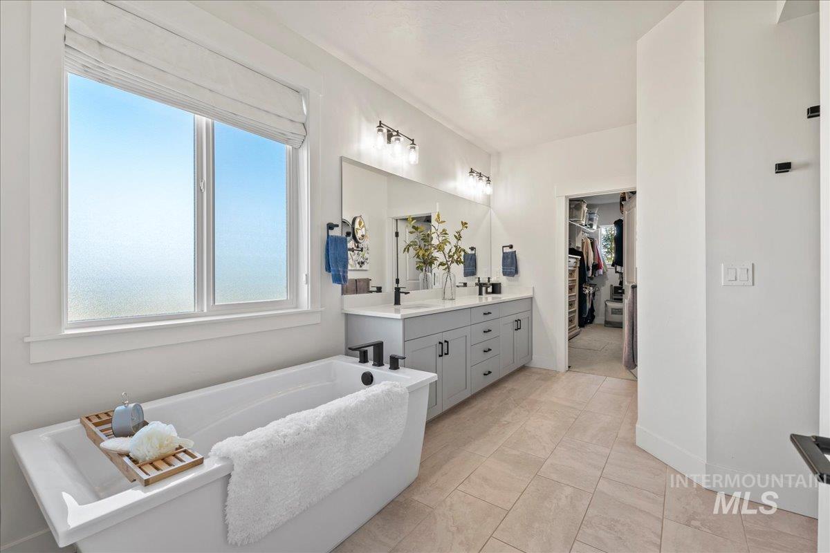 Full bath featuring vanity, a freestanding tub, and a walk in closet