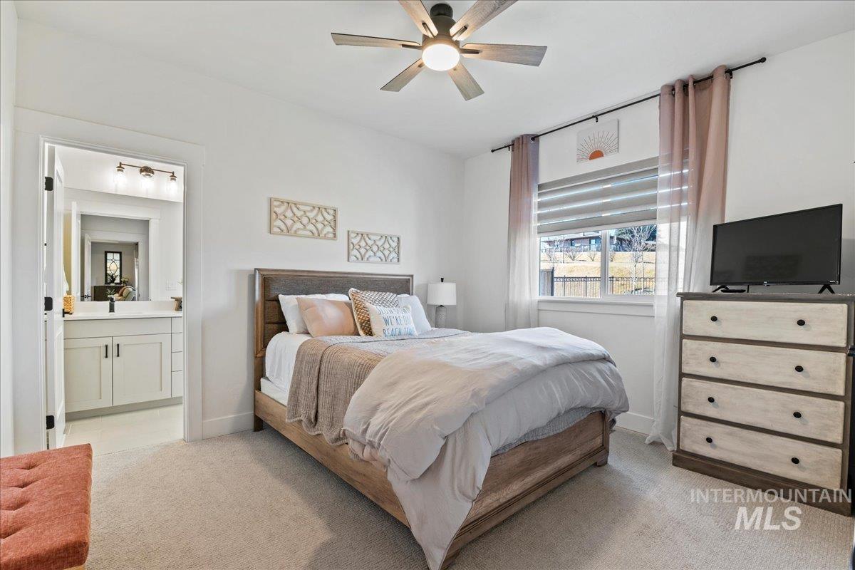 Bedroom featuring light colored carpet, ensuite bath, and ceiling fan