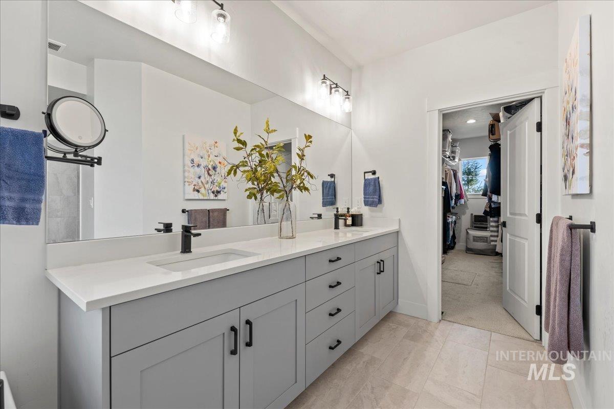 Bathroom with double vanity and a walk in closet