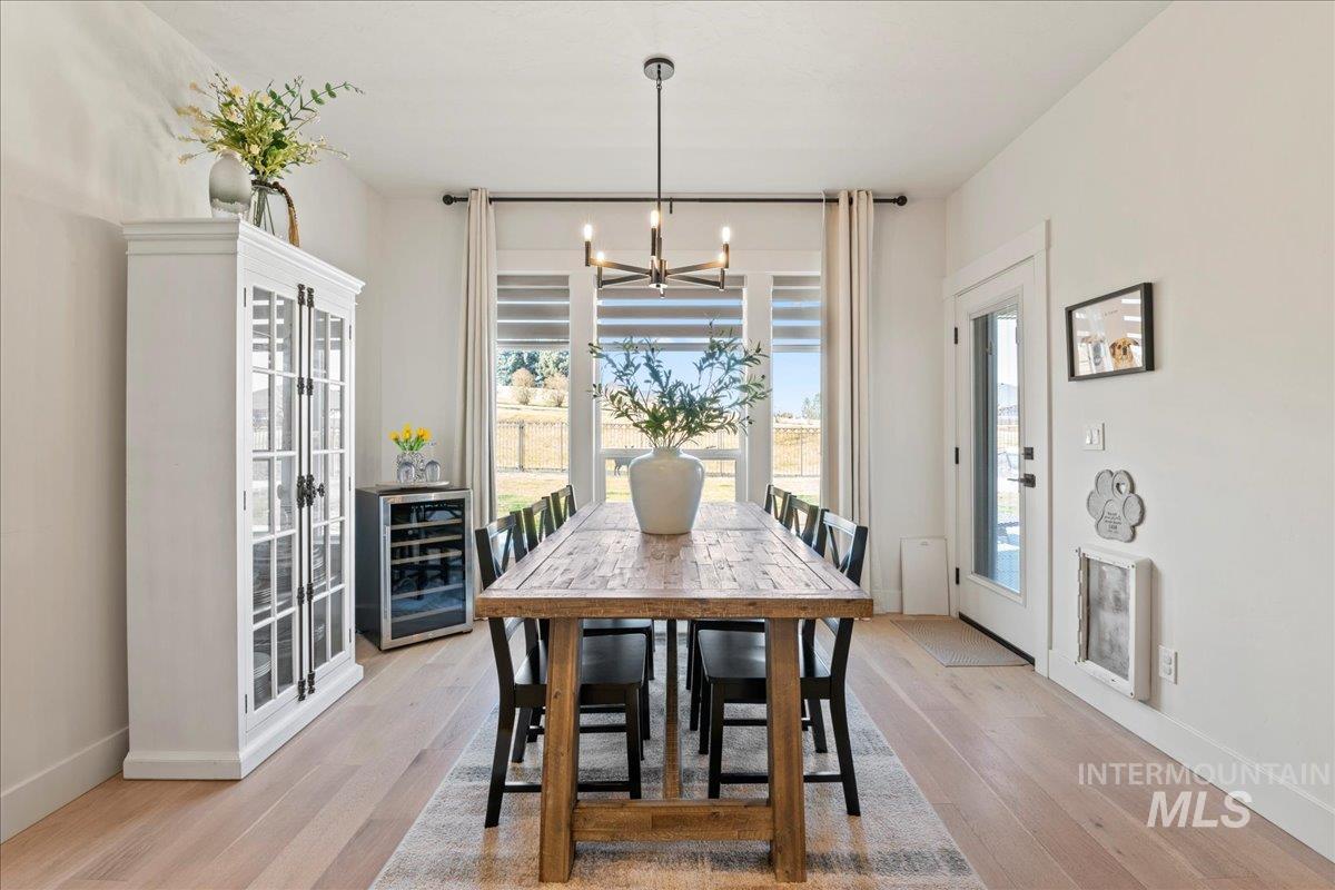Dining room featuring wine cooler, light wood finished floors, and suspended lighting