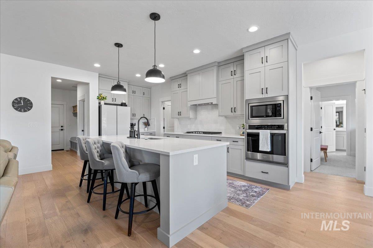 Kitchen with a breakfast bar area, light wood-type flooring, a center island with sink, and stainless steel appliances