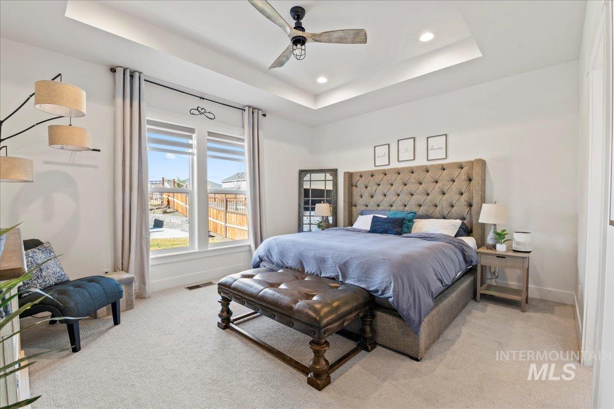 Bedroom featuring a tray ceiling, recessed lighting, ceiling fan, and light colored carpet