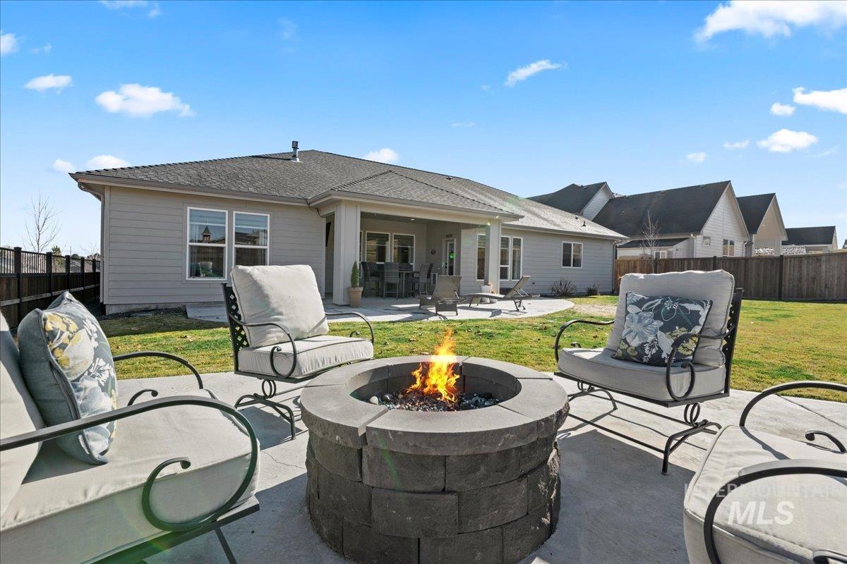 Rear view of house with a patio area, a fenced backyard, roof with shingles, and a fire pit
