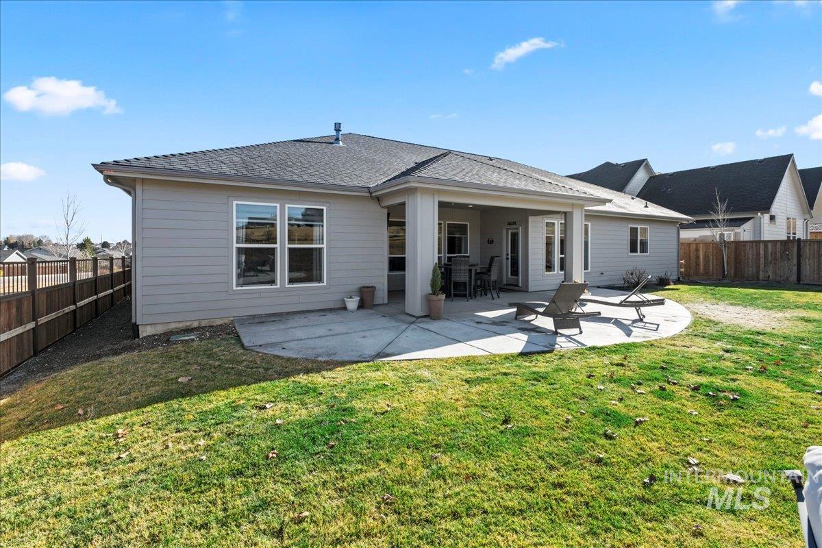 Back of house featuring a patio, a fenced backyard, and a shingled roof