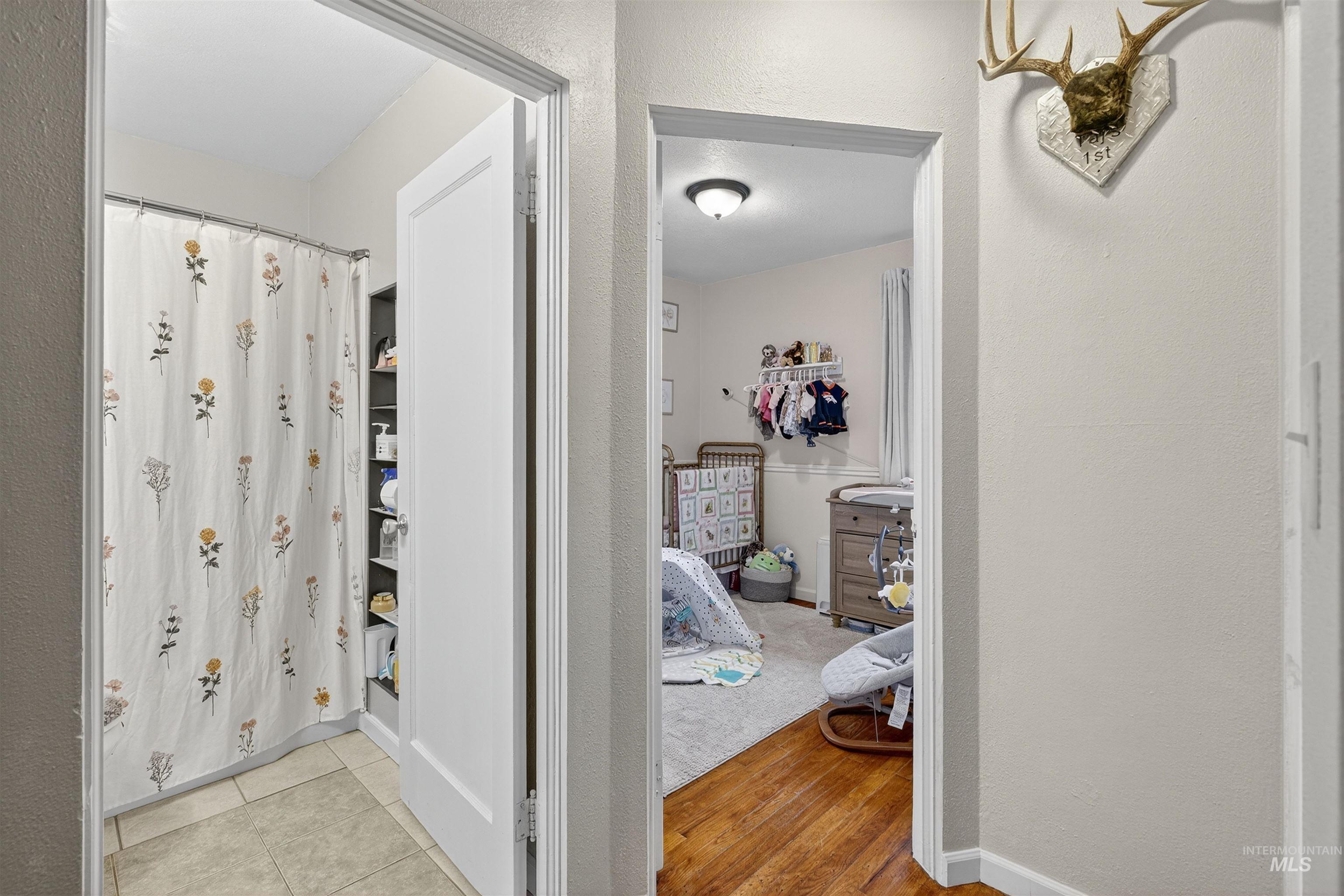 Full bath with a textured wall, light wood-style floors, and curtained shower
