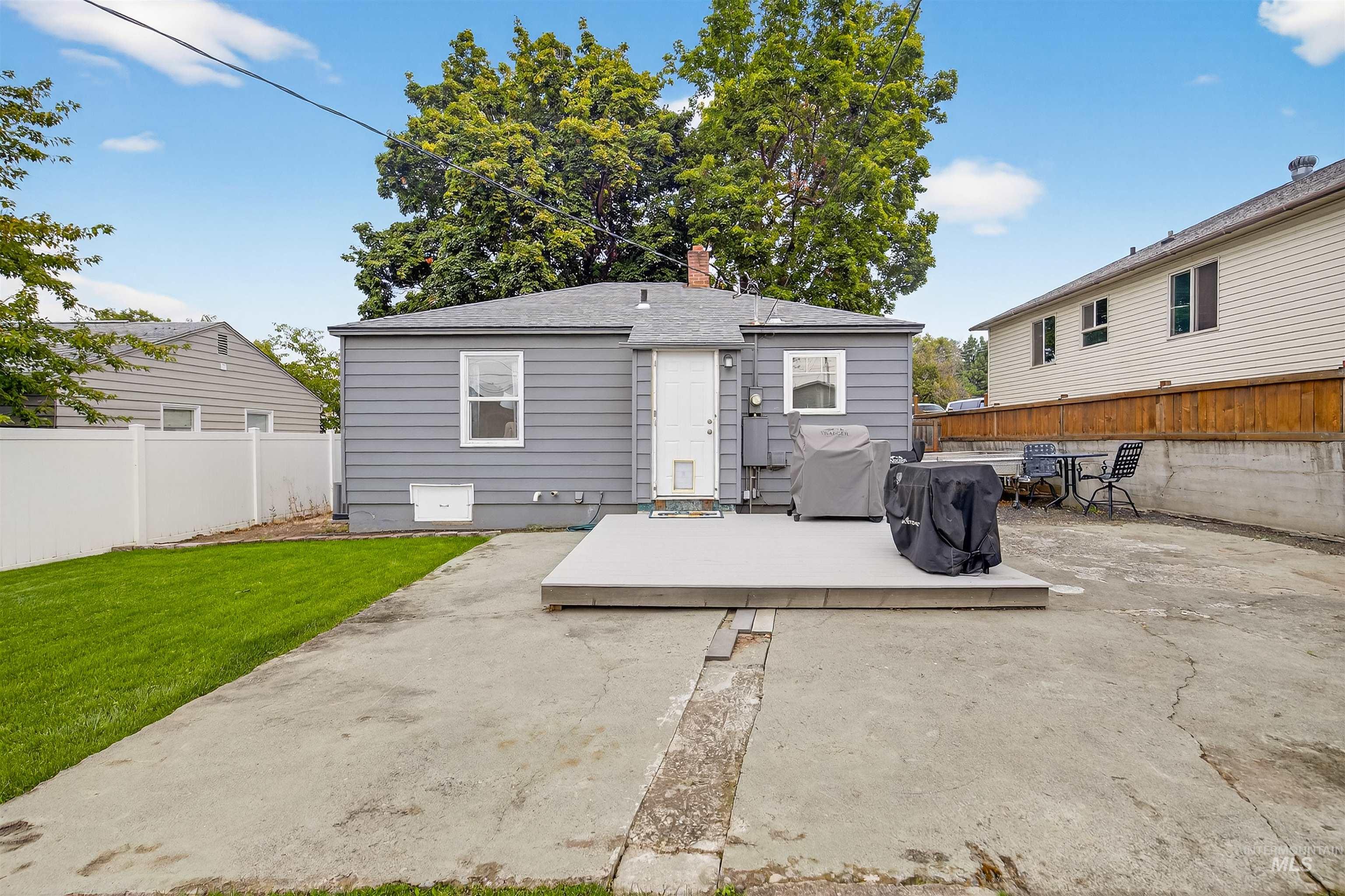 Back of property with a fenced backyard, a chimney, a patio, and a wooden deck