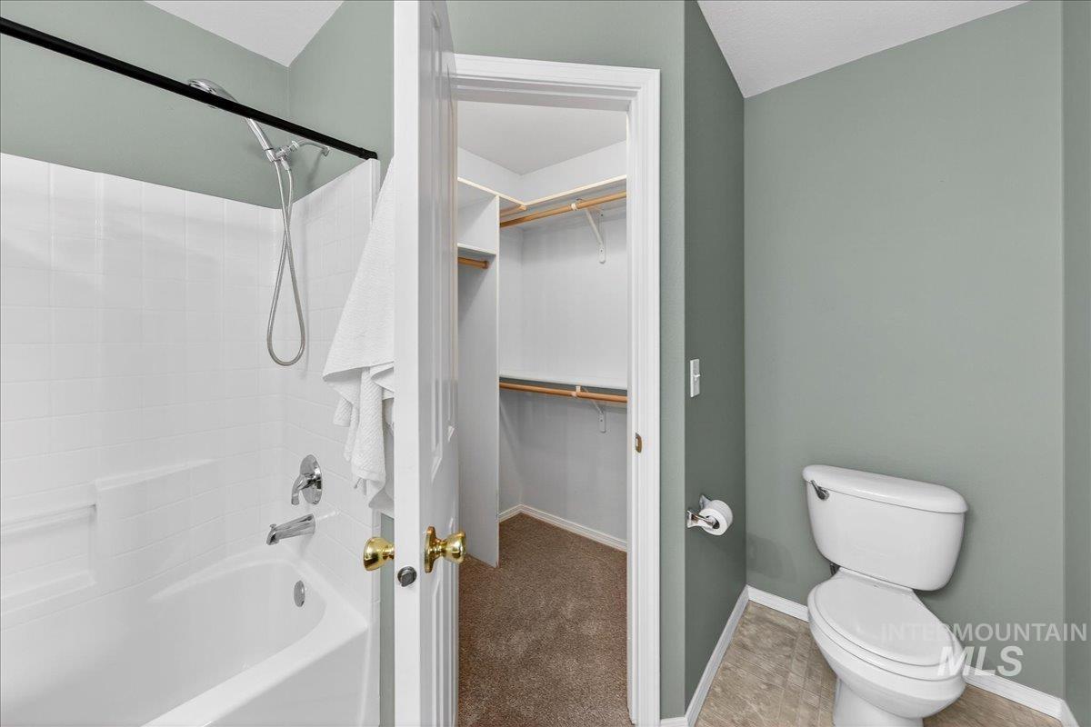 Bathroom with a walk in closet, shower / bath combination, and carpet