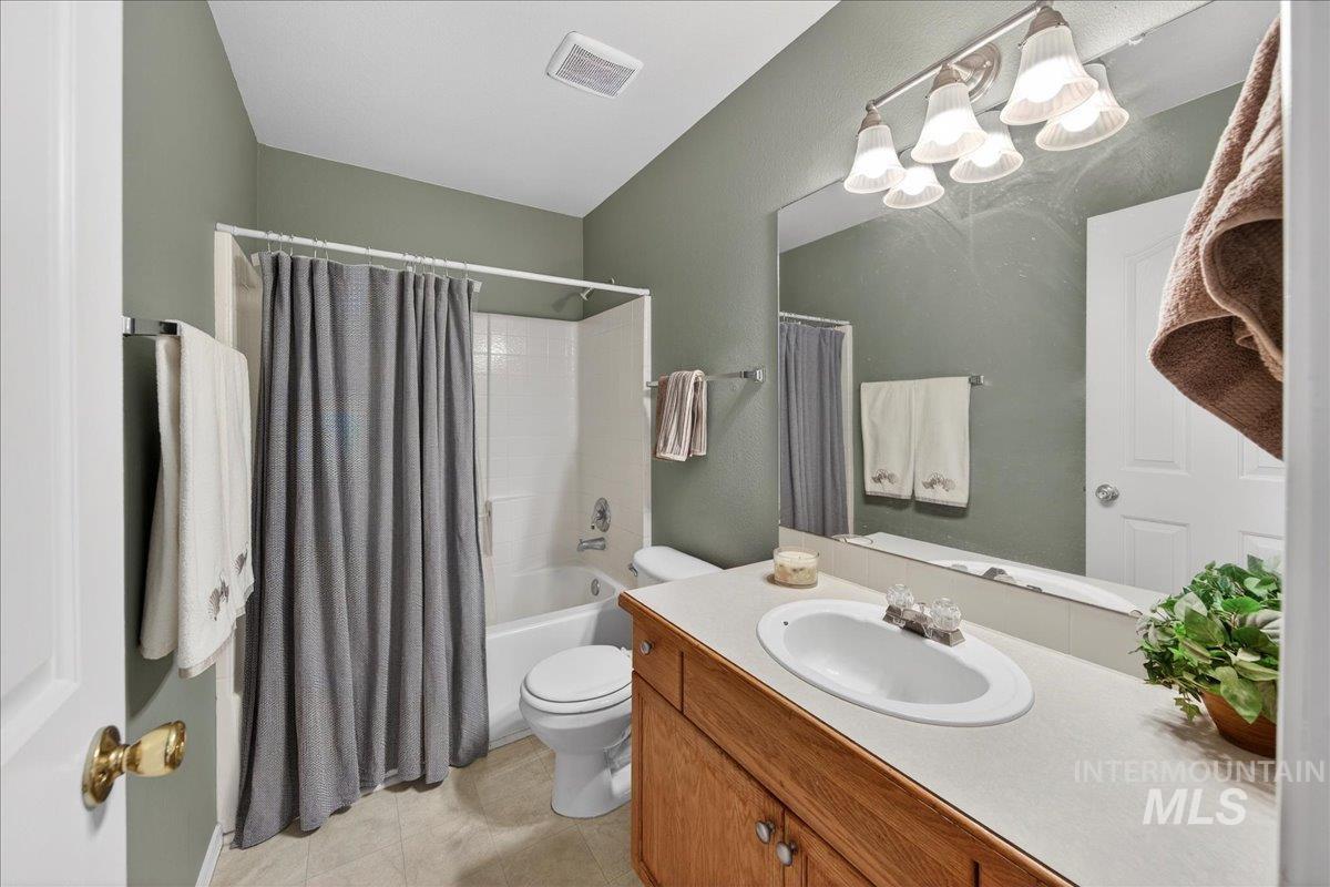 Full bath with shower / tub combo, vanity, a chandelier, and a textured wall