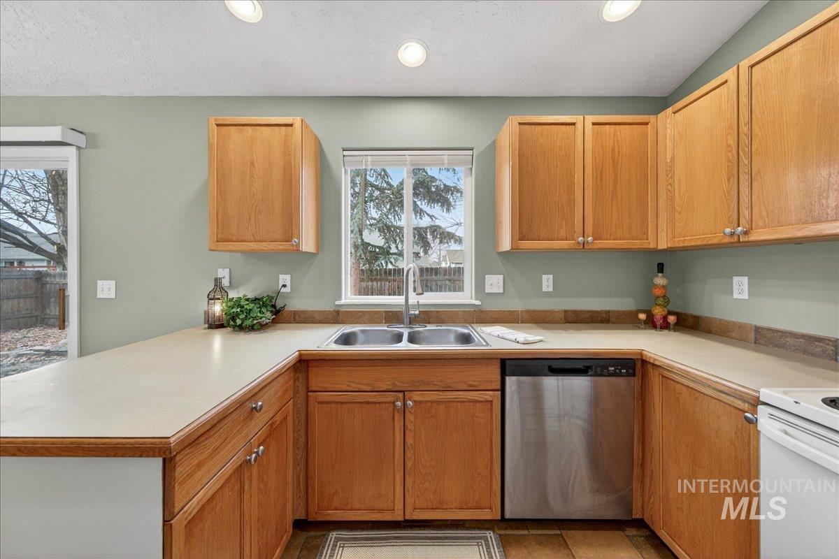 Kitchen featuring dishwasher, light countertops, white range with electric stovetop, recessed lighting, and a peninsula