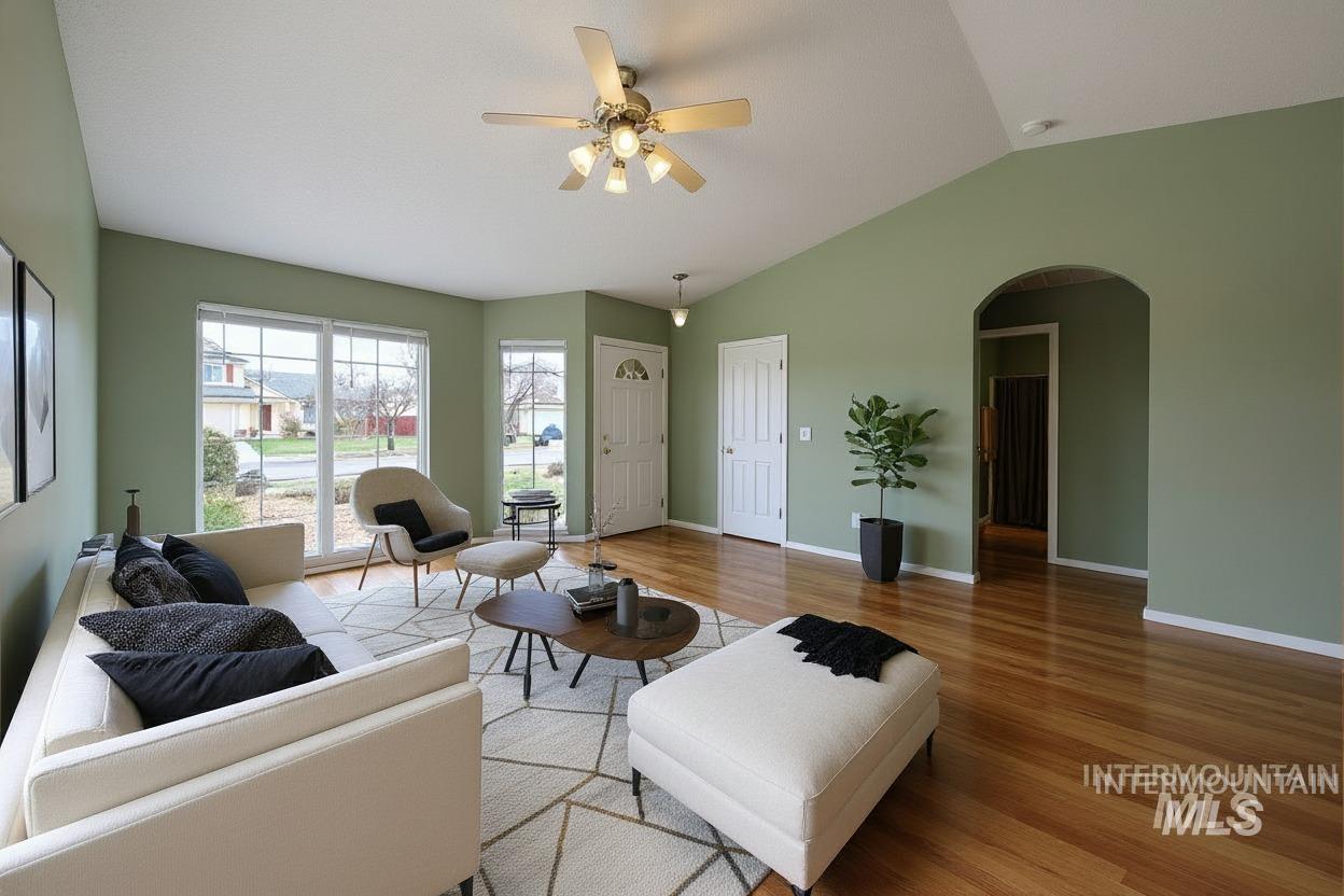 Living room with arched walkways, wood finished floors, lofted ceiling, and a ceiling fan