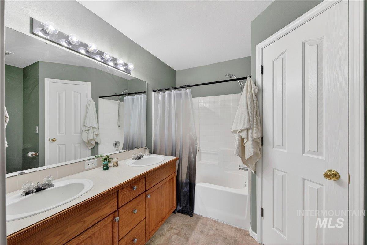 Bathroom featuring shower / bath combo with shower curtain and double vanity