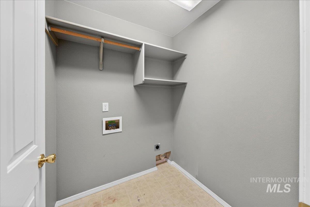 Washroom with light floors, electric dryer hookup, and hookup for a washing machine