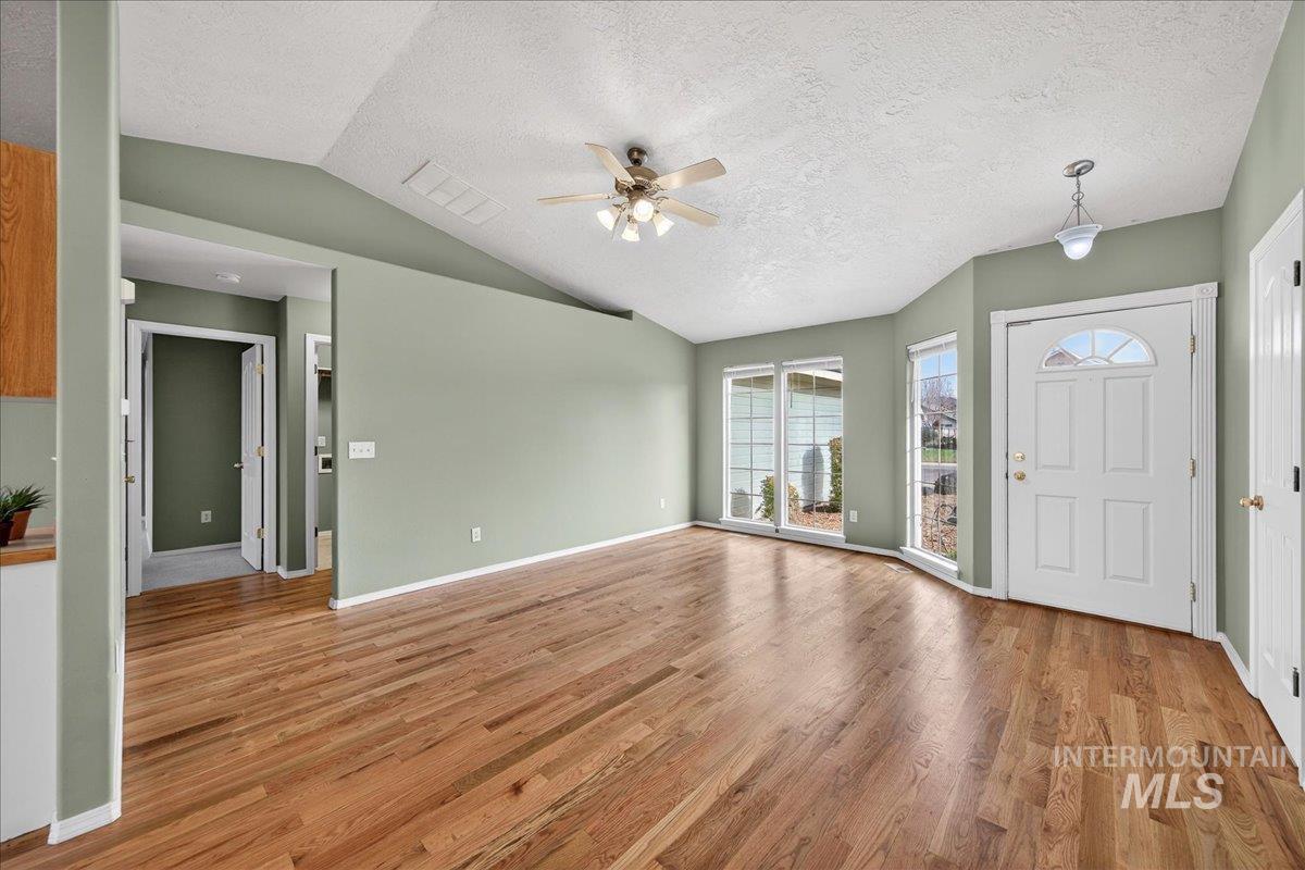Foyer featuring lofted ceiling, a textured ceiling, a ceiling fan, and light wood-style flooring