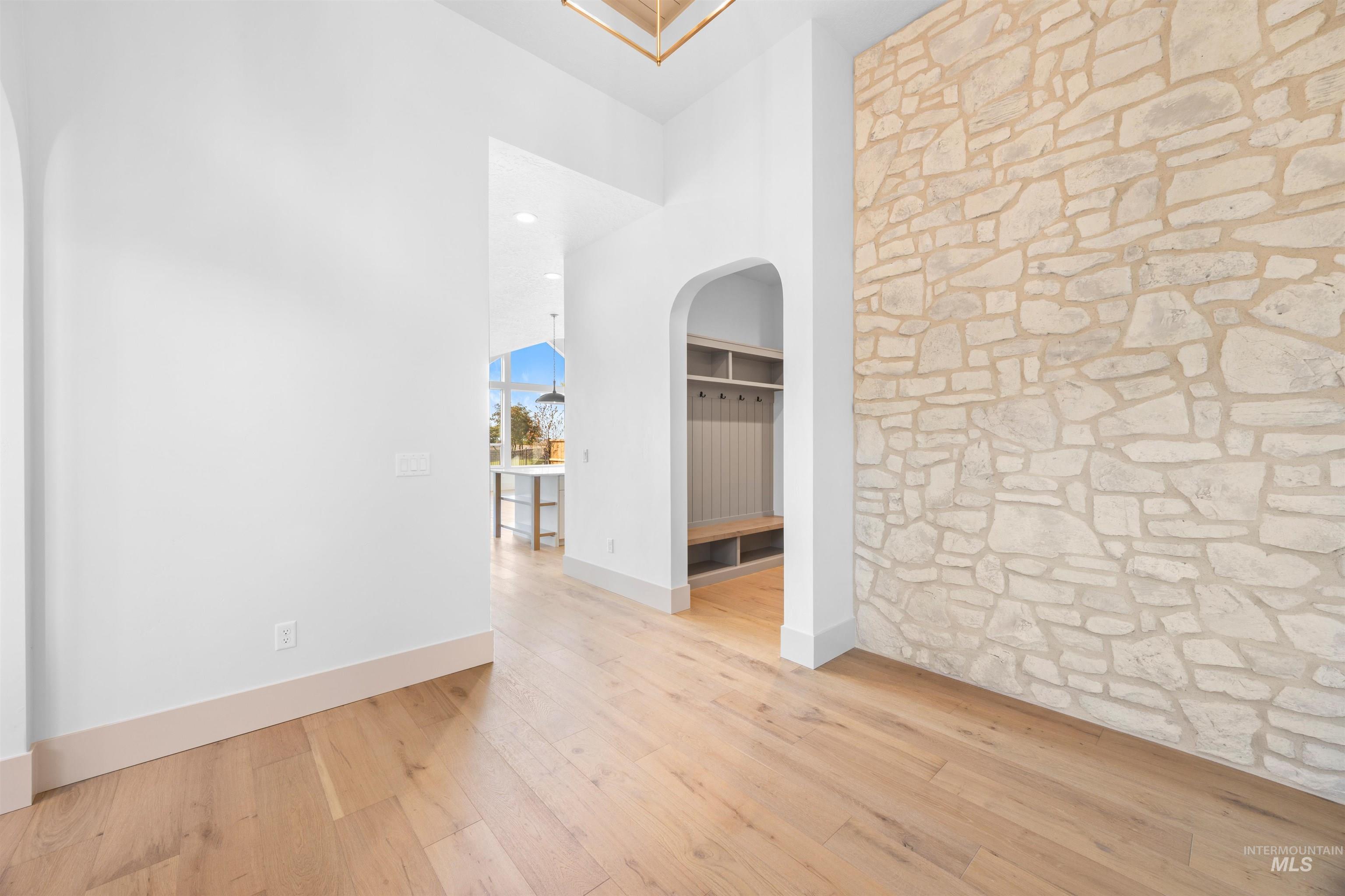 Hall with light wood-style flooring, a towering ceiling, arched walkways, and recessed lighting