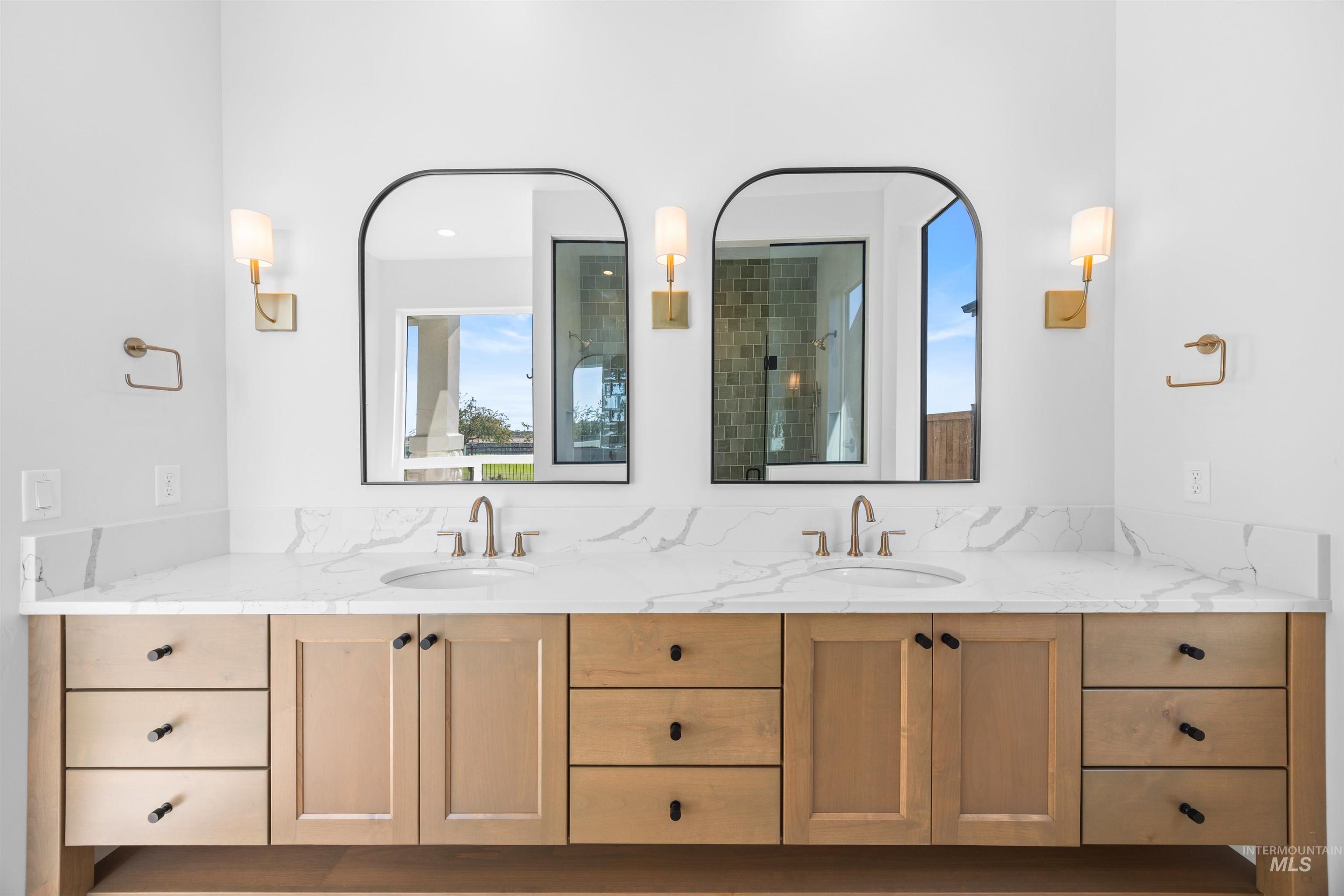 Bathroom with double vanity, plenty of natural light, and a tile shower