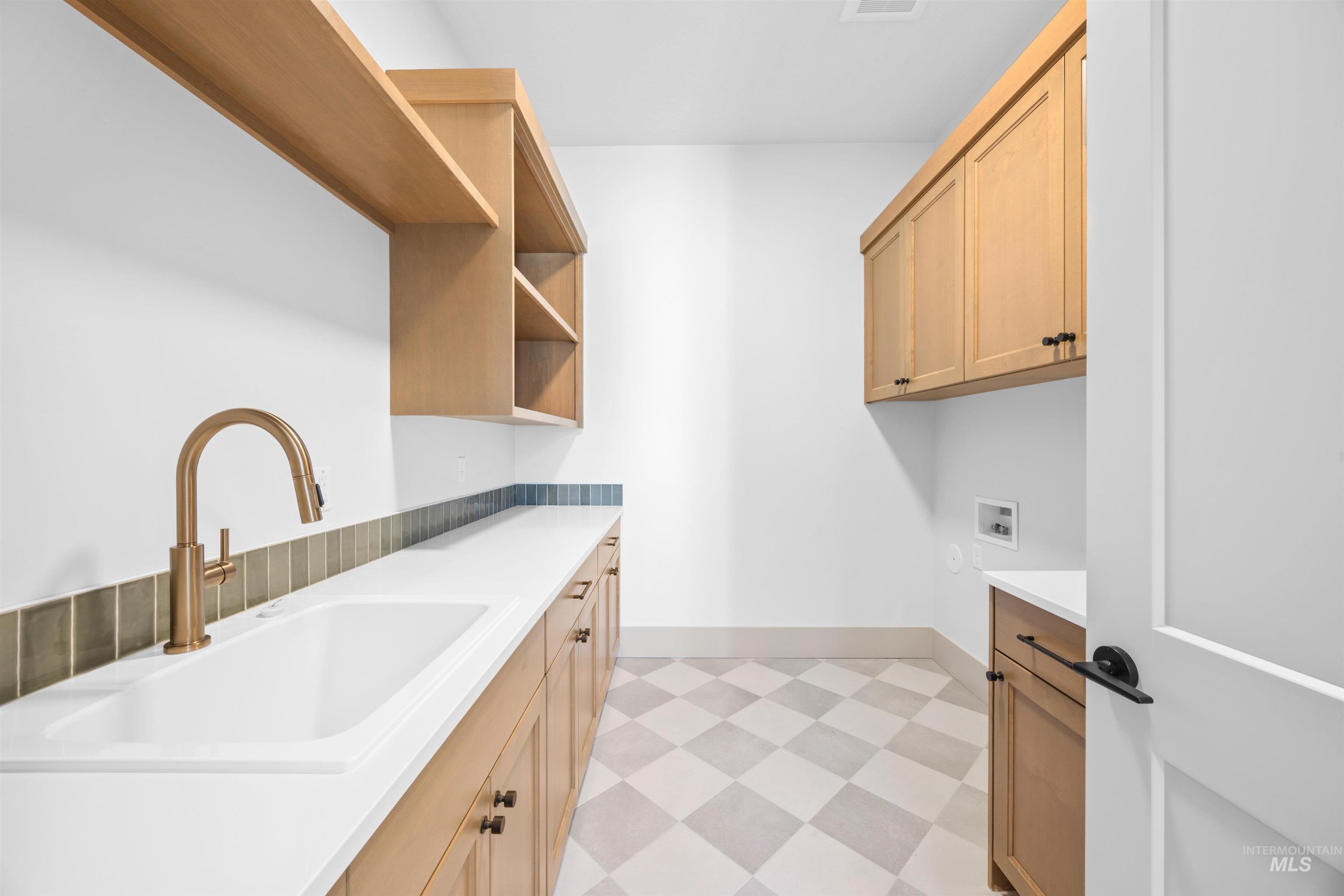 Washroom with light floors, hookup for a washing machine, and cabinet space