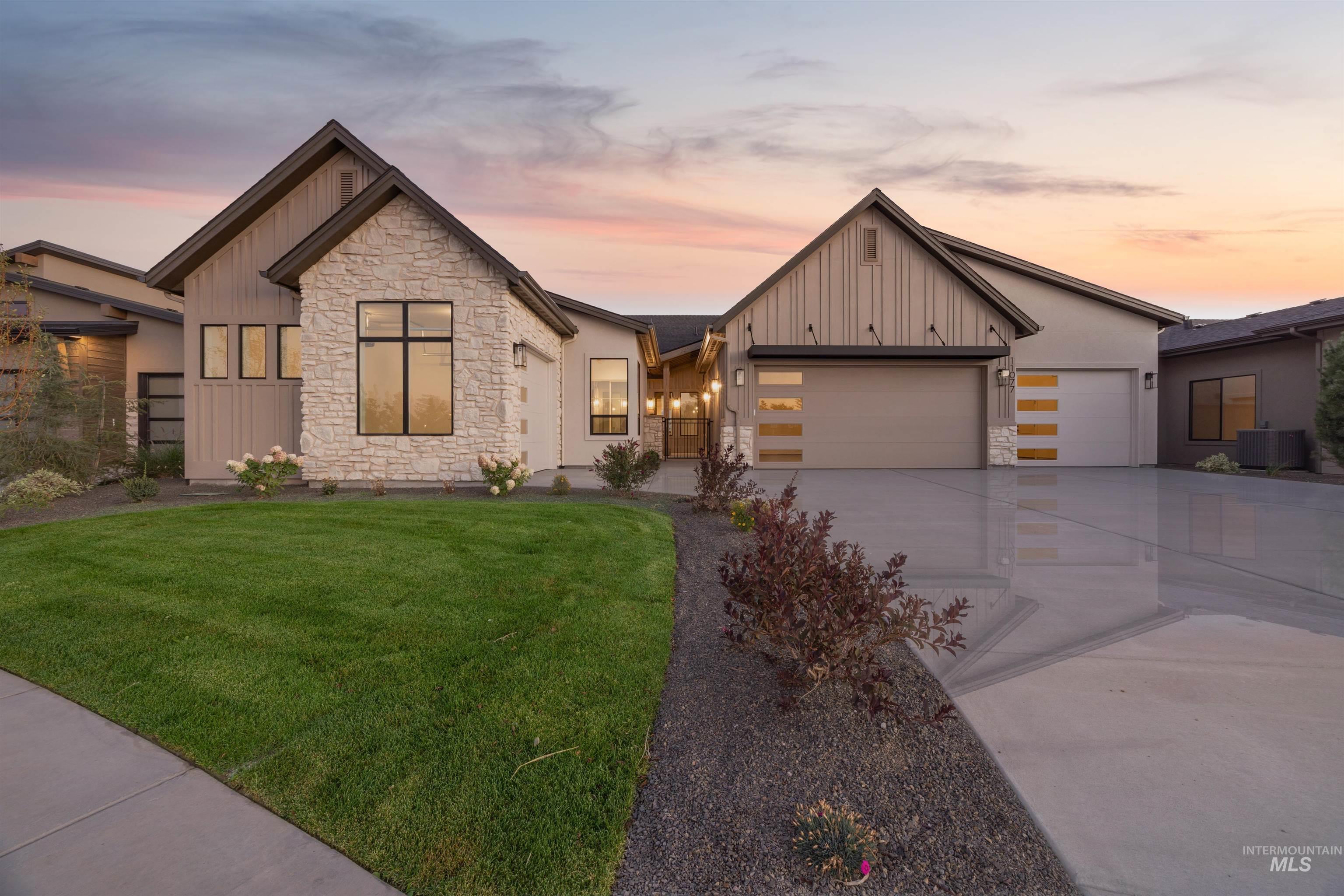 Modern inspired farmhouse with board and batten siding, stone siding, concrete driveway, and a front yard