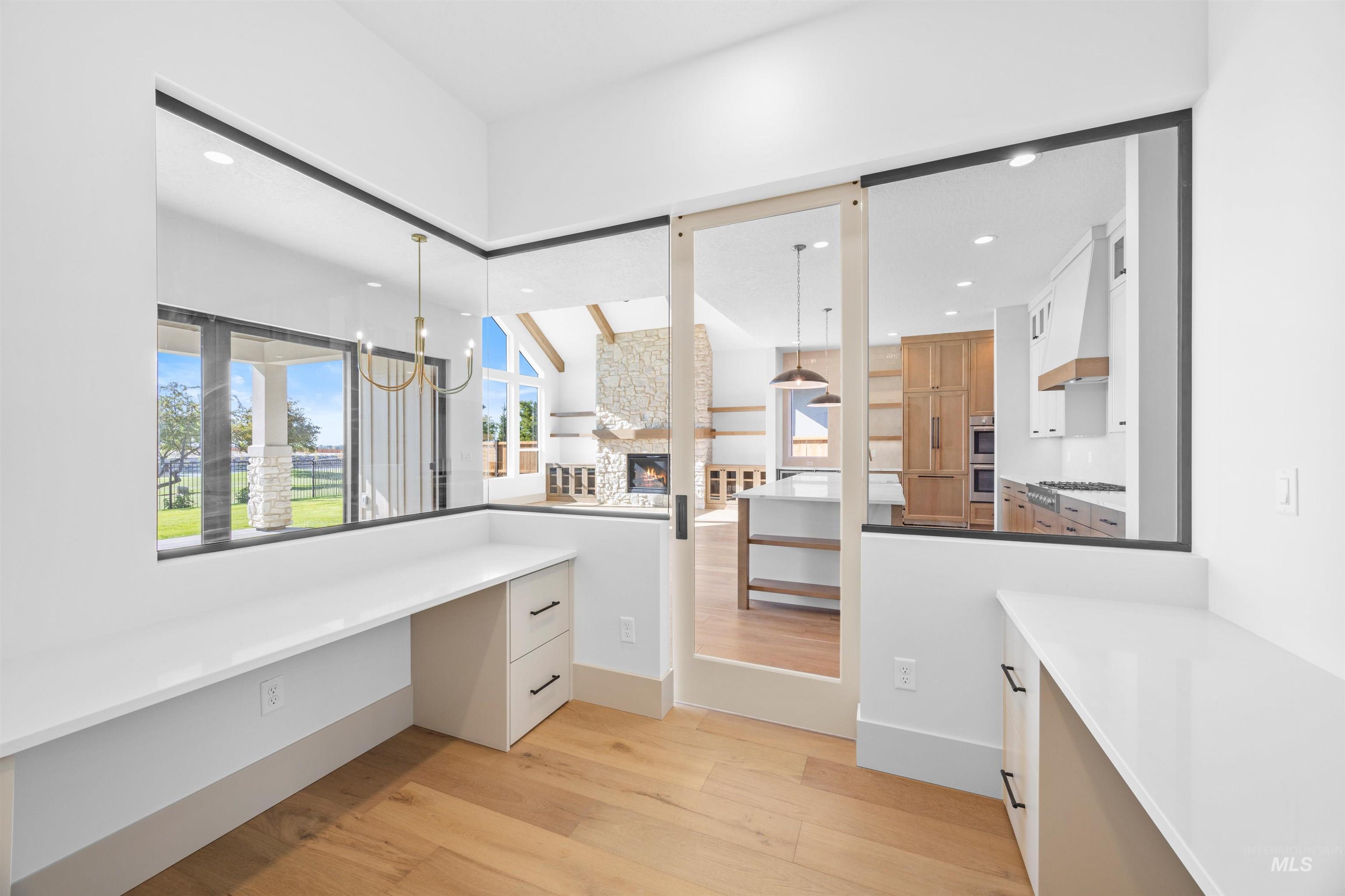 Unfurnished office with light wood finished floors, recessed lighting, a fireplace, and built in study area