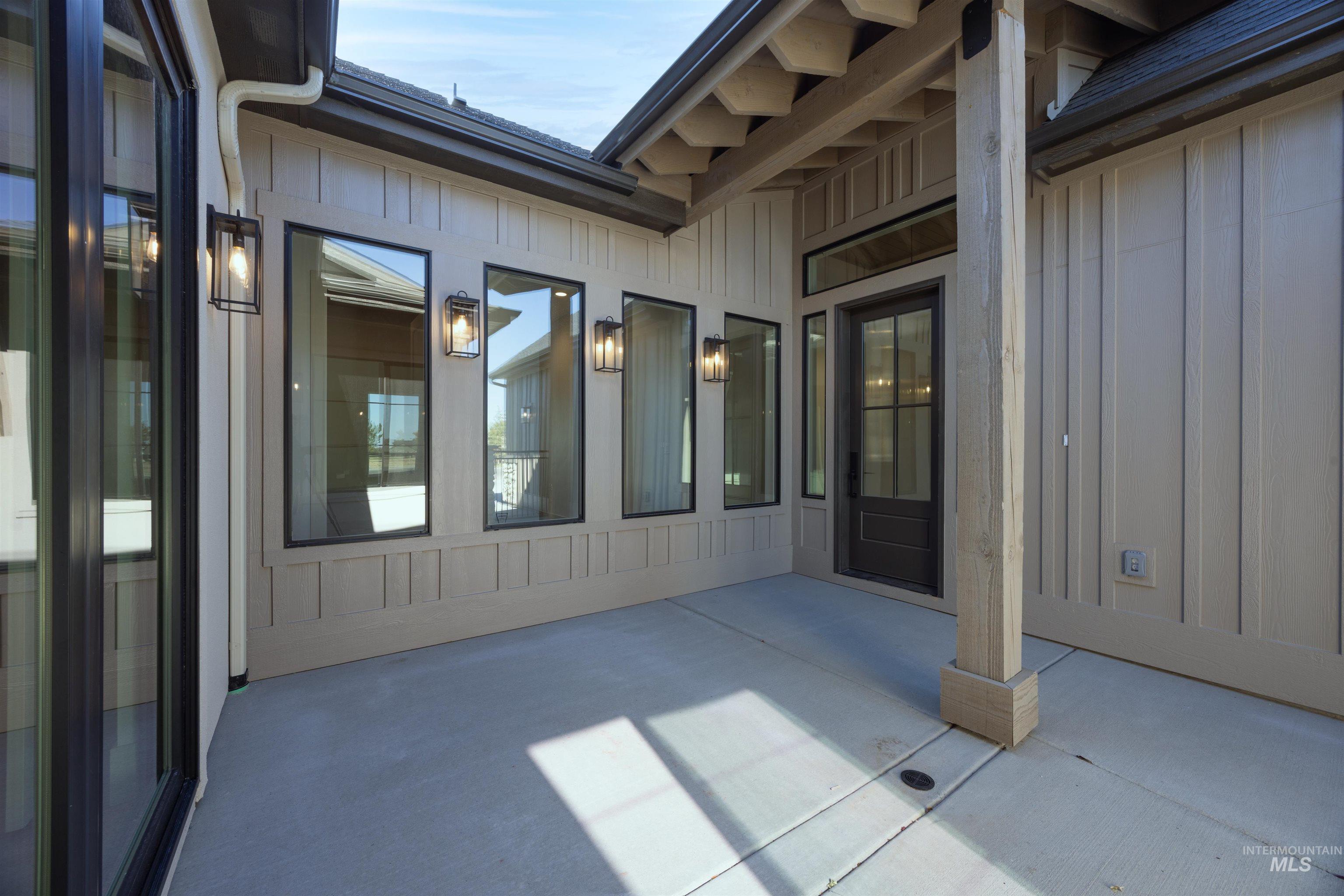 View of exterior entry featuring board and batten siding and a patio