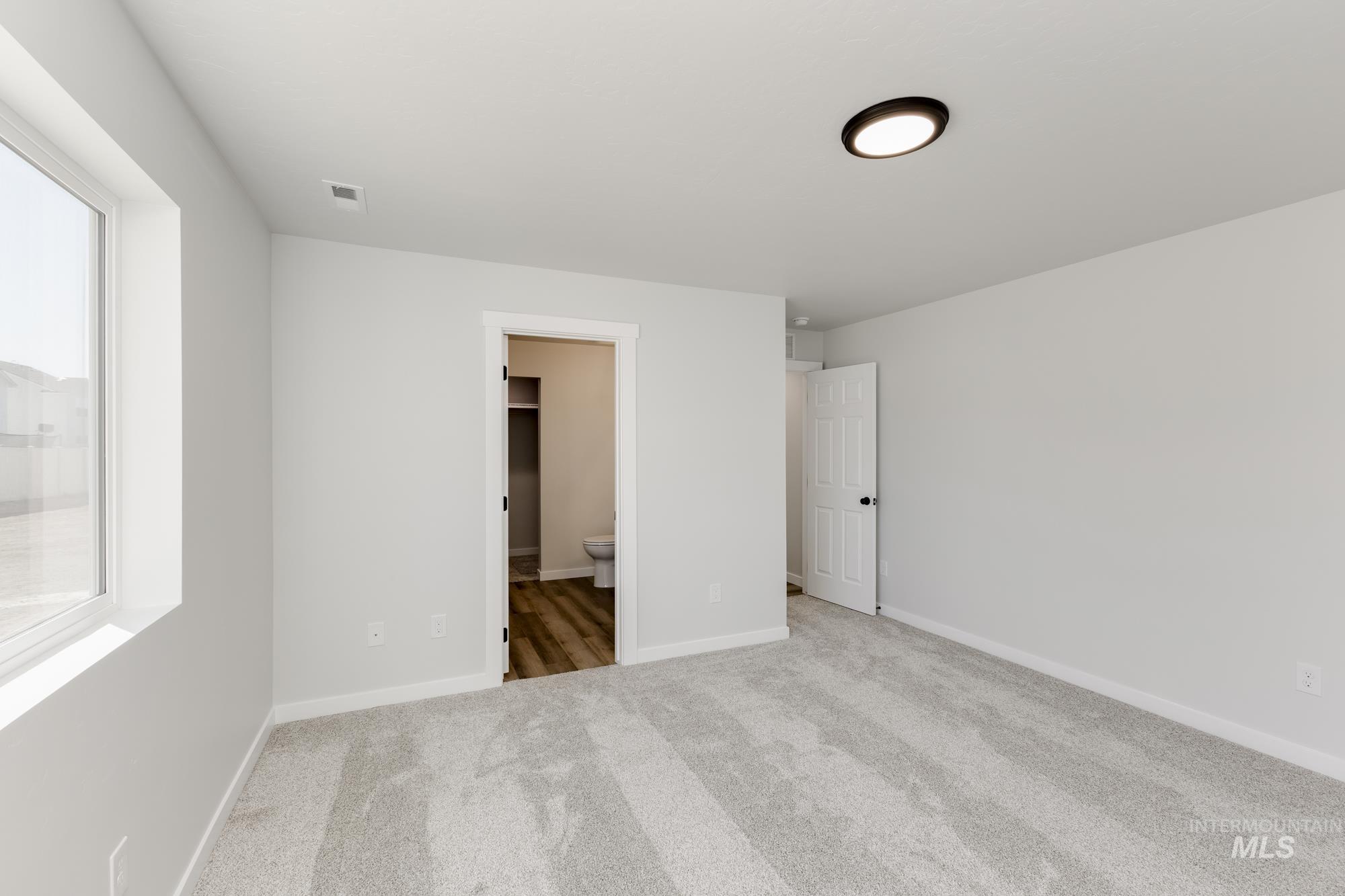 Unfurnished bedroom with ensuite bathroom and carpet floors