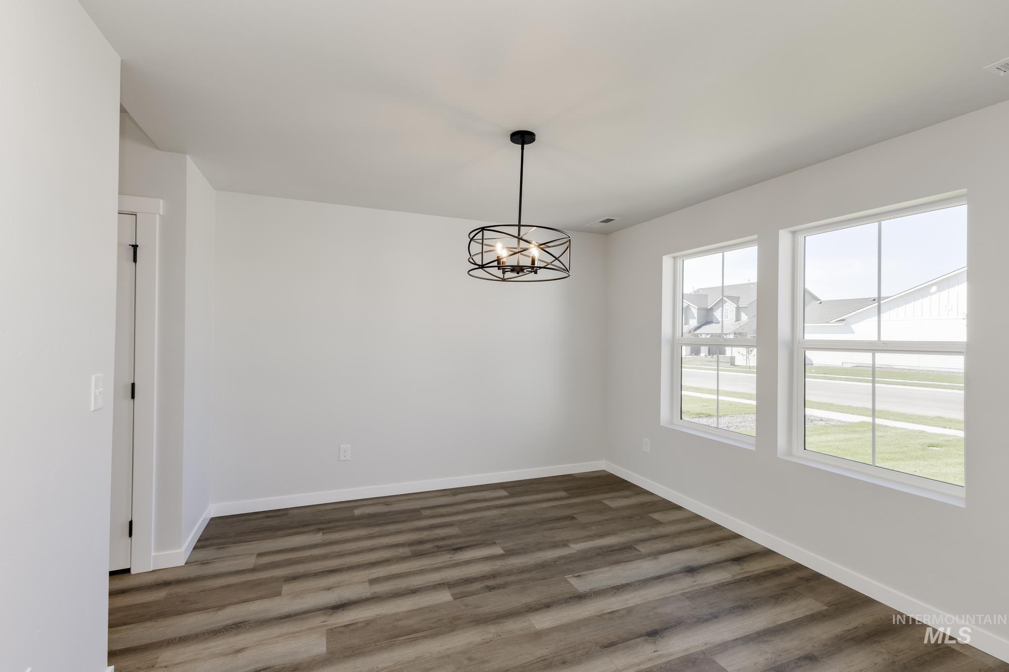 Unfurnished dining area with a chandelier and dark wood-style flooring