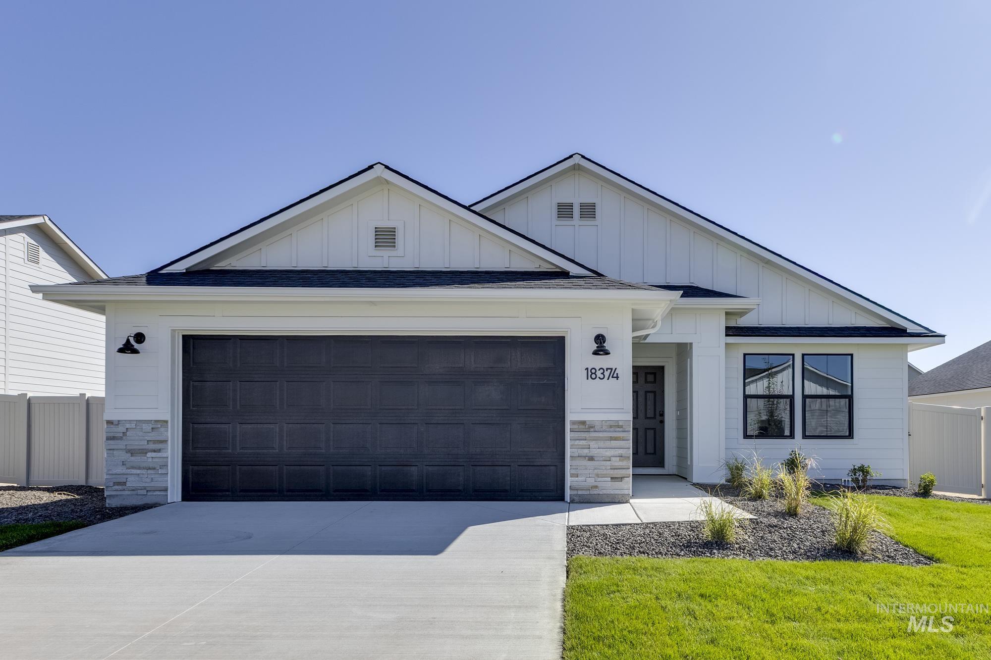 Modern farmhouse style home with board and batten siding, stone siding, concrete driveway, and an attached garage