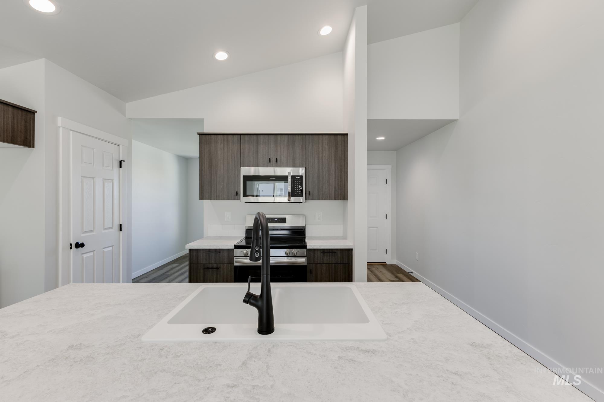 Kitchen featuring recessed lighting, appliances with stainless steel finishes, modern cabinets, dark brown cabinetry, and high vaulted ceiling