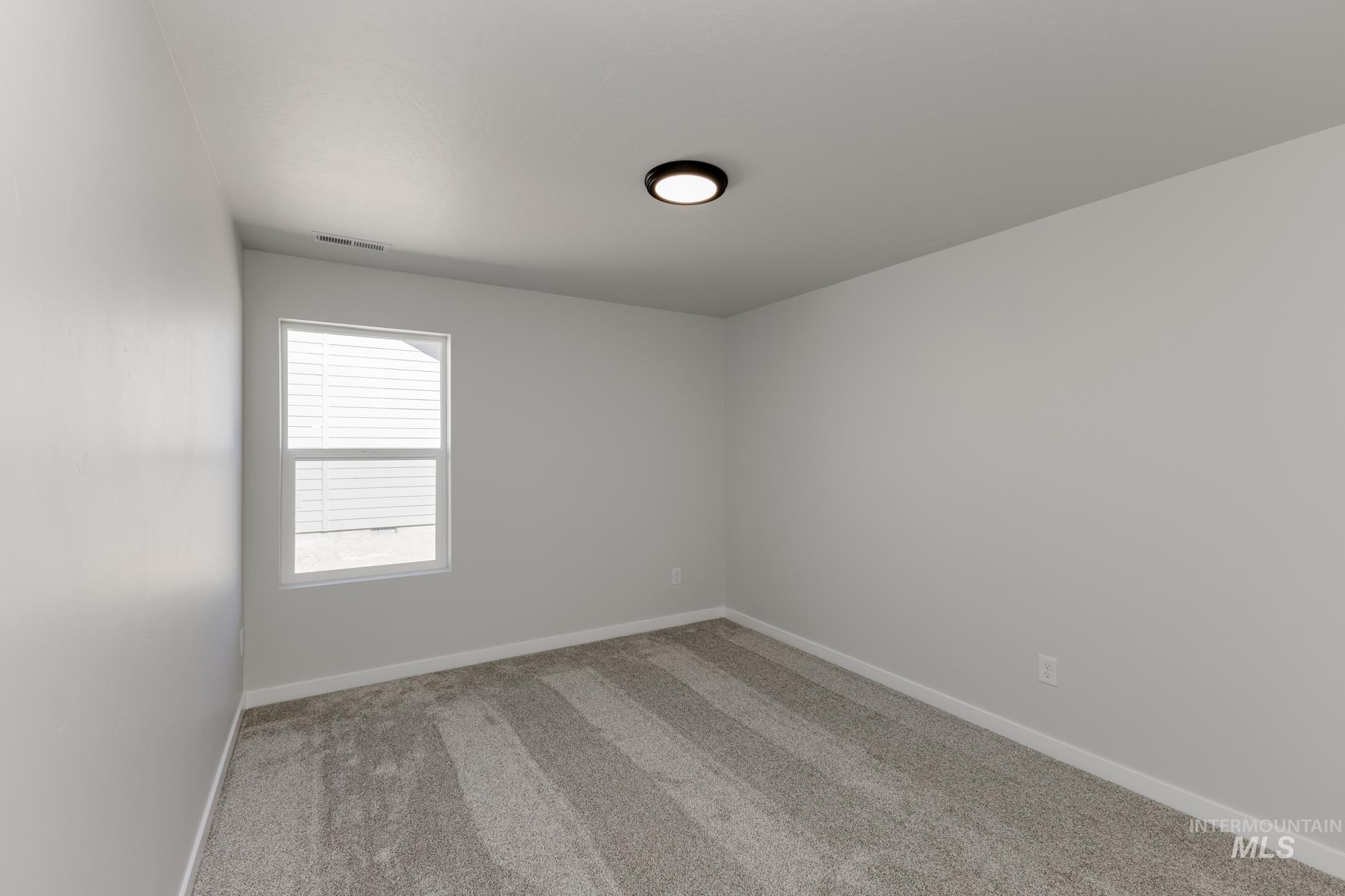 Carpeted spare room with baseboards