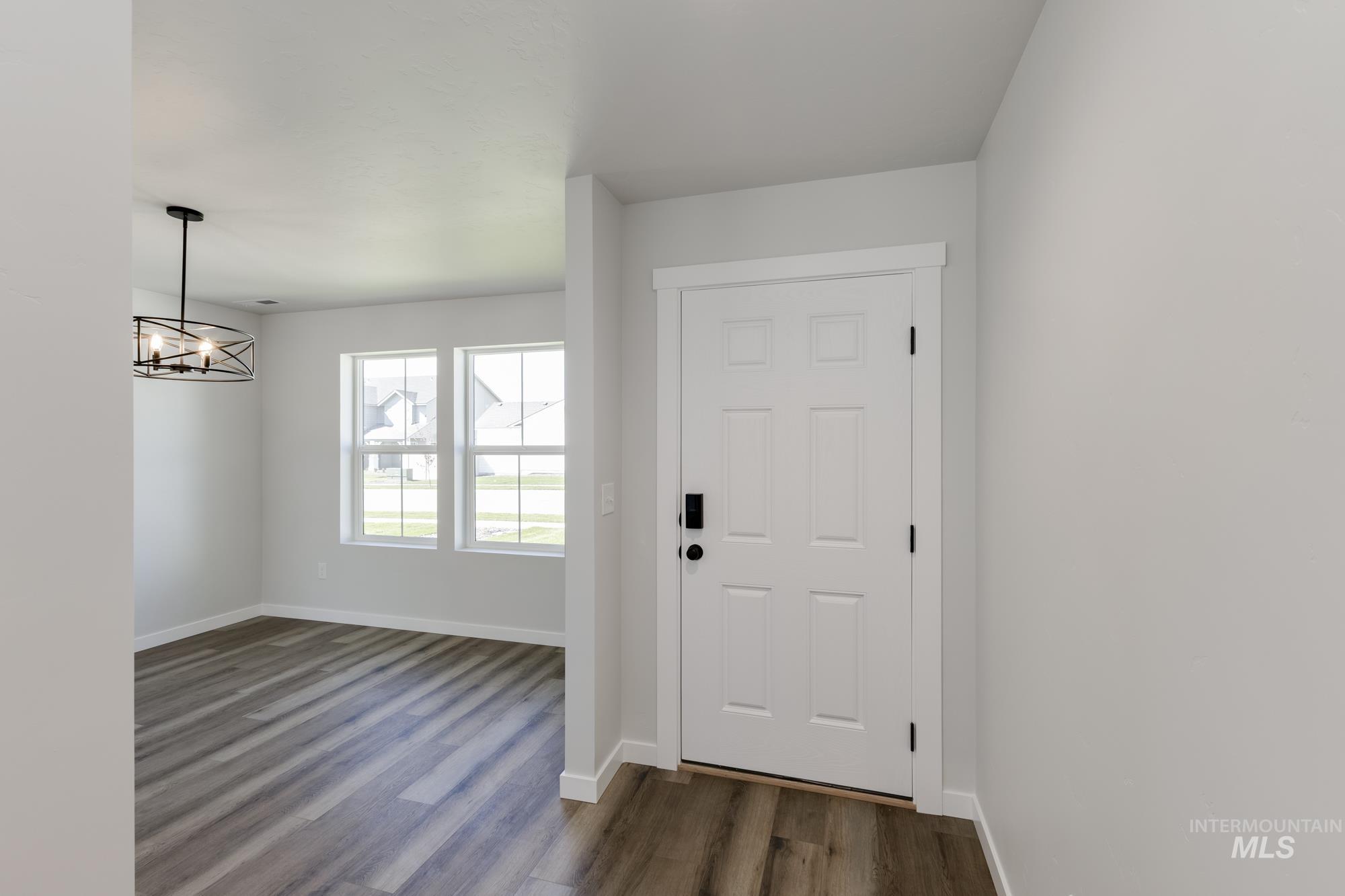 Entryway with dark wood-style flooring and a chandelier