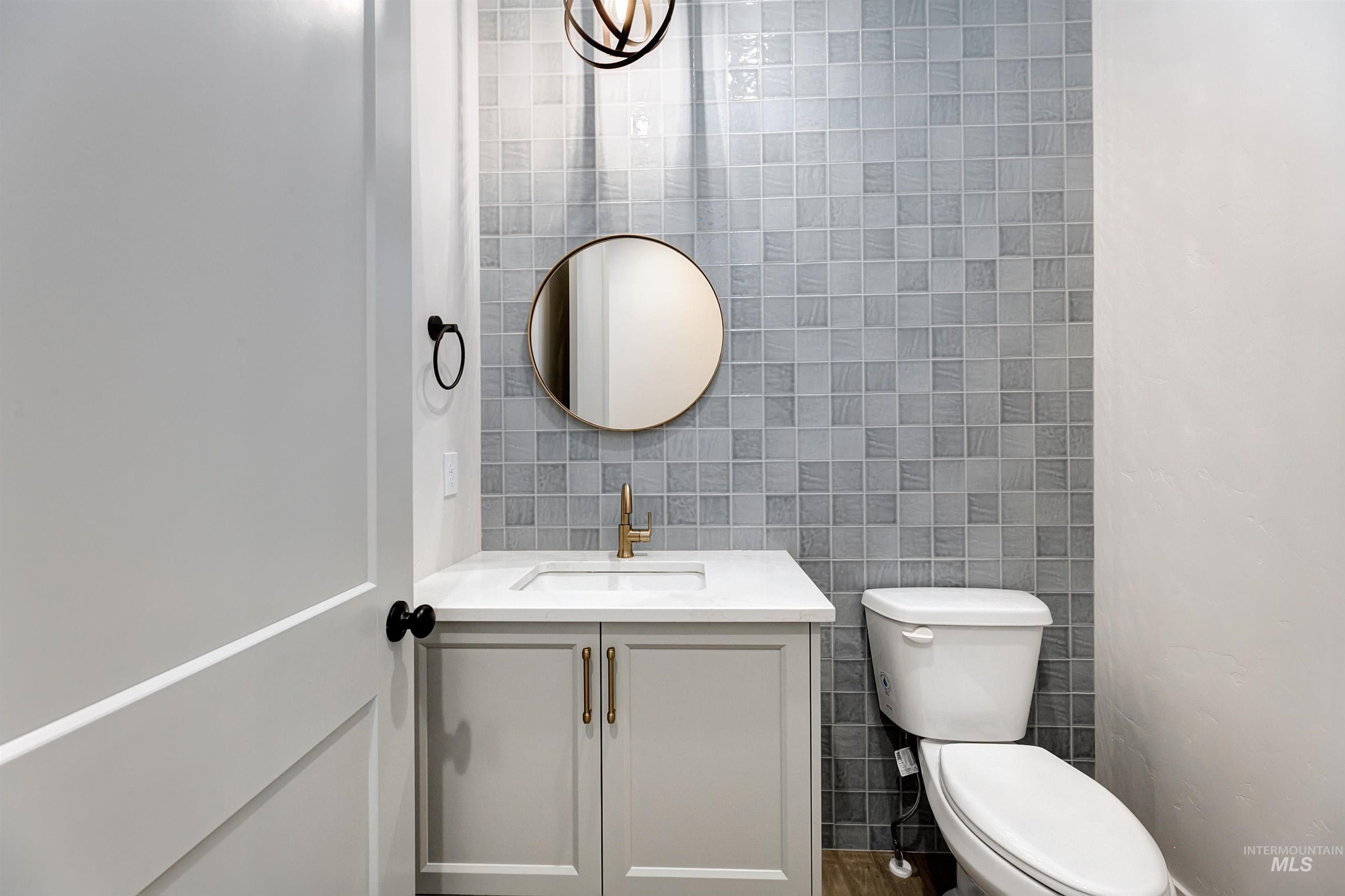 Half bathroom featuring tile walls, vanity, and decorative backsplash