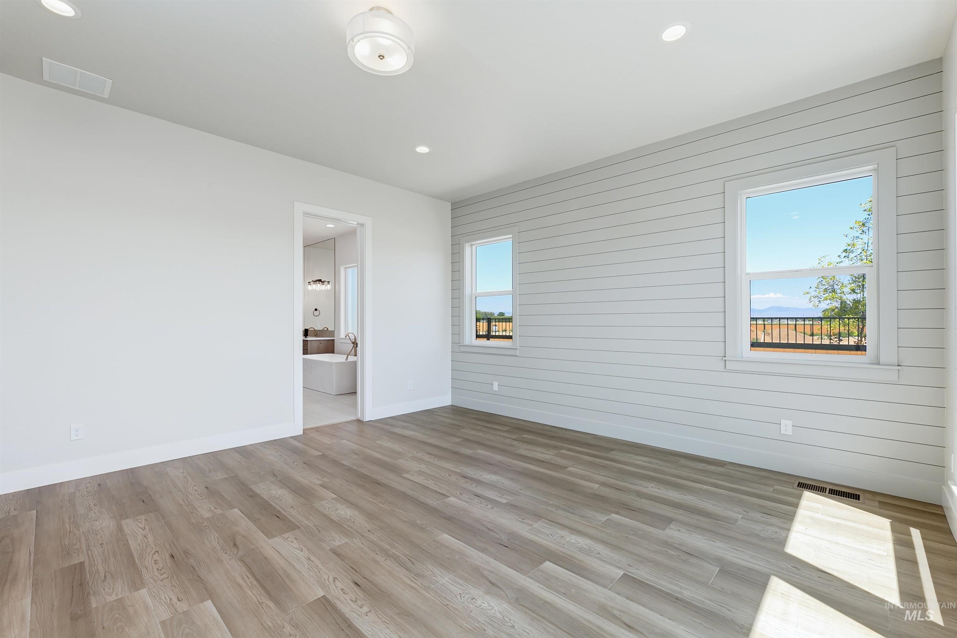 Empty room with wood walls, light wood finished floors, and recessed lighting