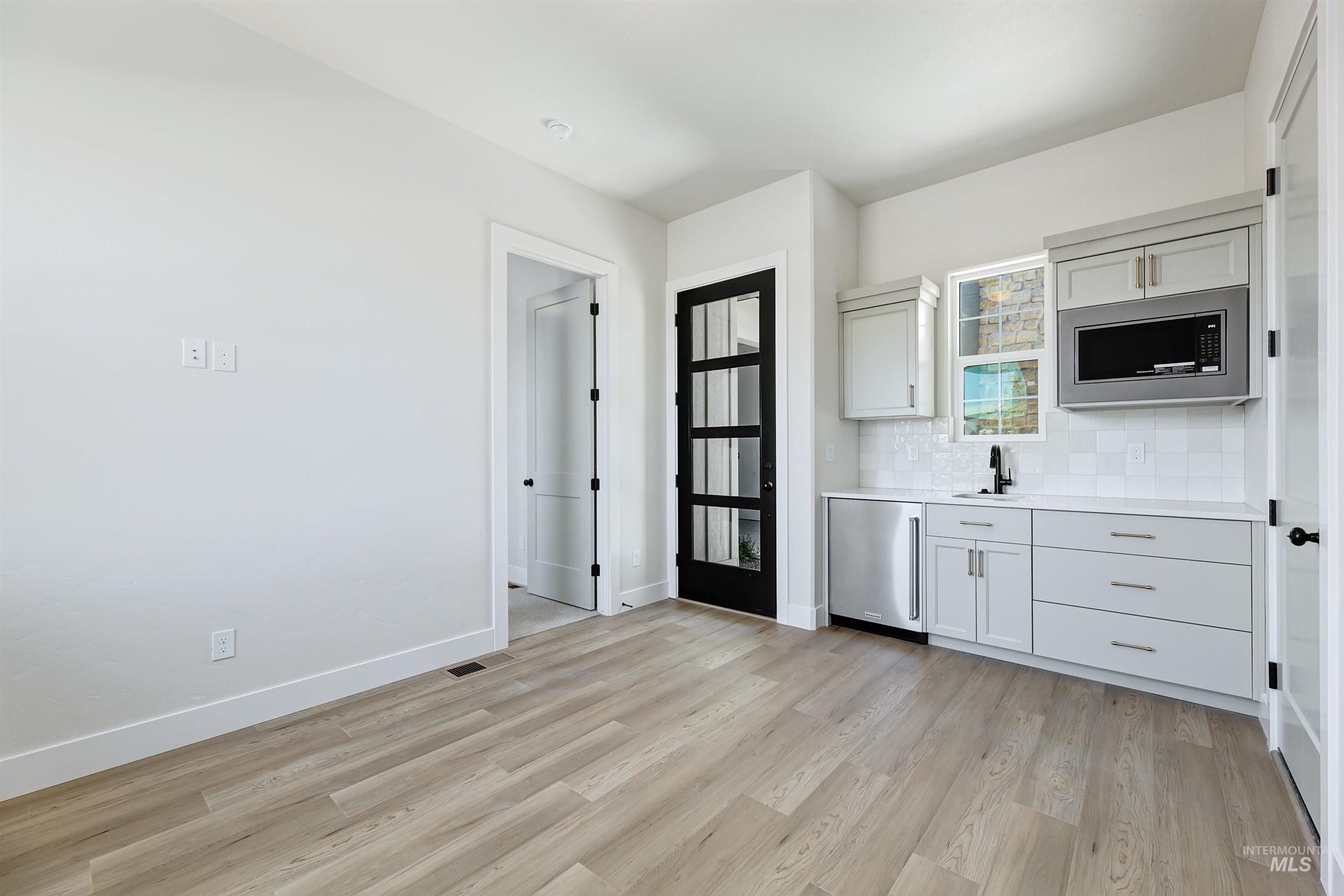 Kitchen featuring light countertops, light wood finished floors, stainless steel appliances, and decorative backsplash