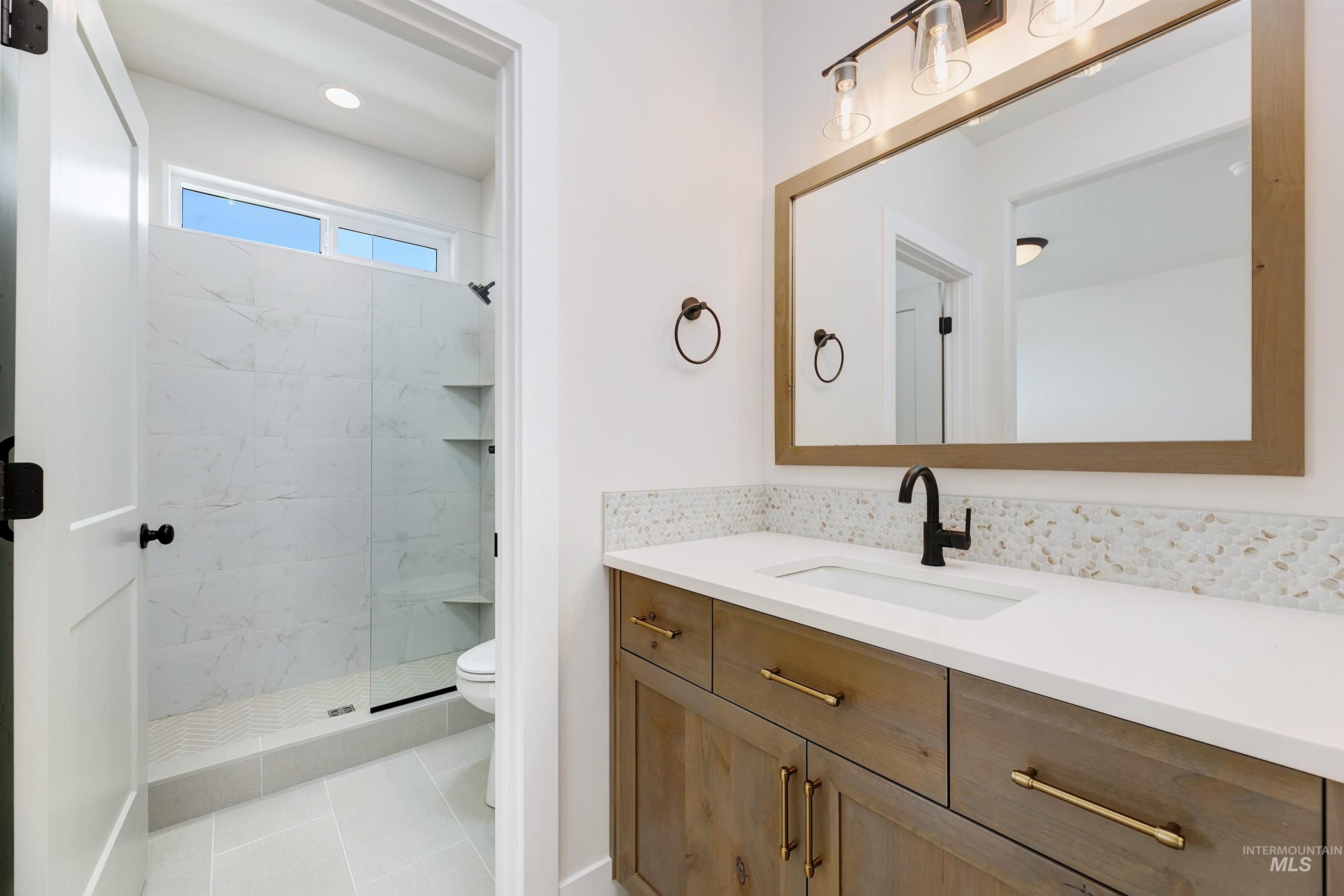 Full bathroom featuring vanity, a marble finish shower, and light tile patterned floors