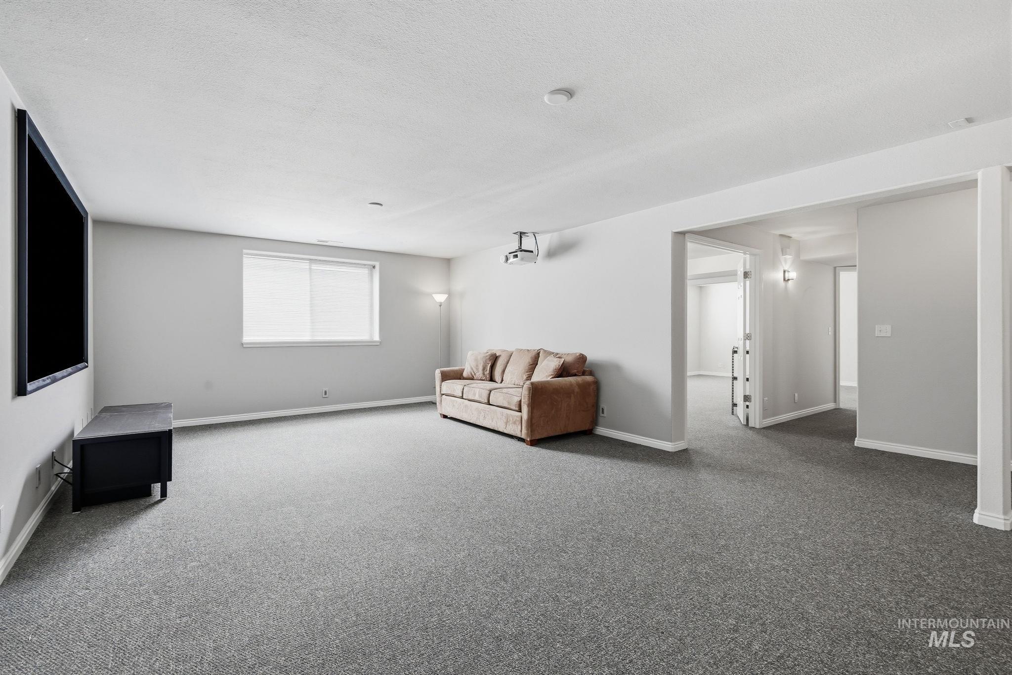 Spacious room featuring gray wall-to-wall carpeting, a window with blinds, and recessed lighting
