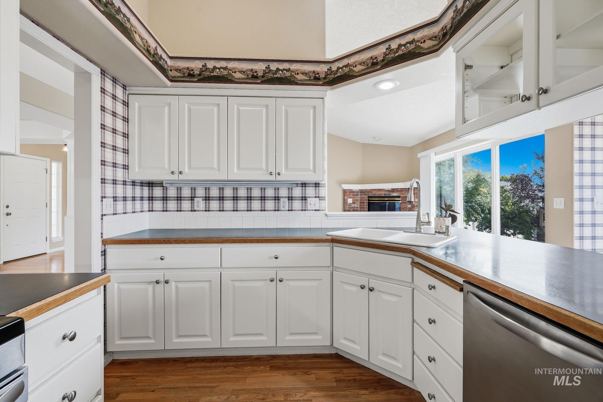 Kitchen featuring white cabinetry, dark countertops, a stainless steel dishwasher, and a window above the sink