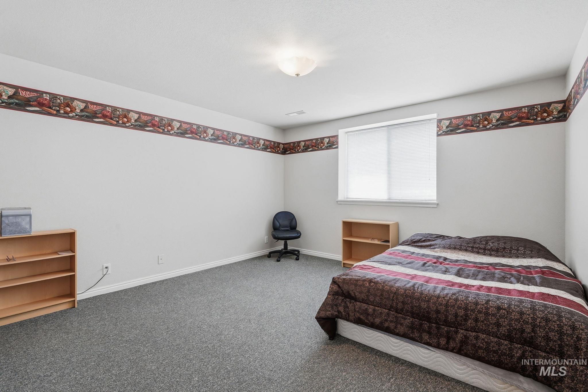Bedroom featuring light gray walls, gray carpet flooring, and a single window with white blinds