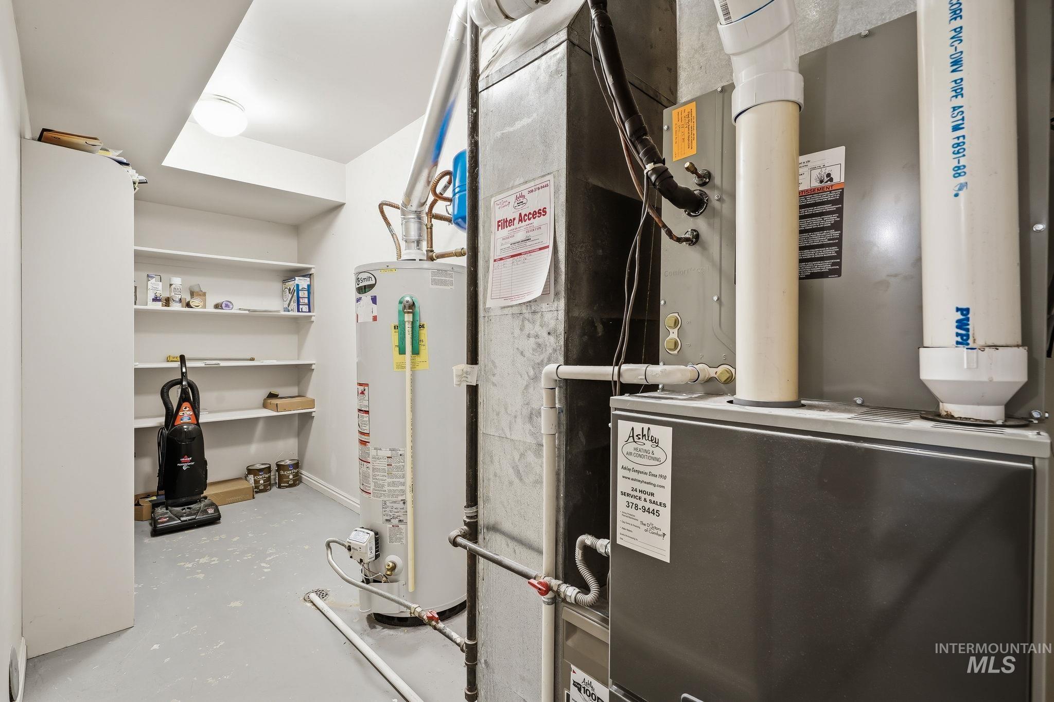 Dedicated utility room featuring a forced-air furnace system and hot water heater