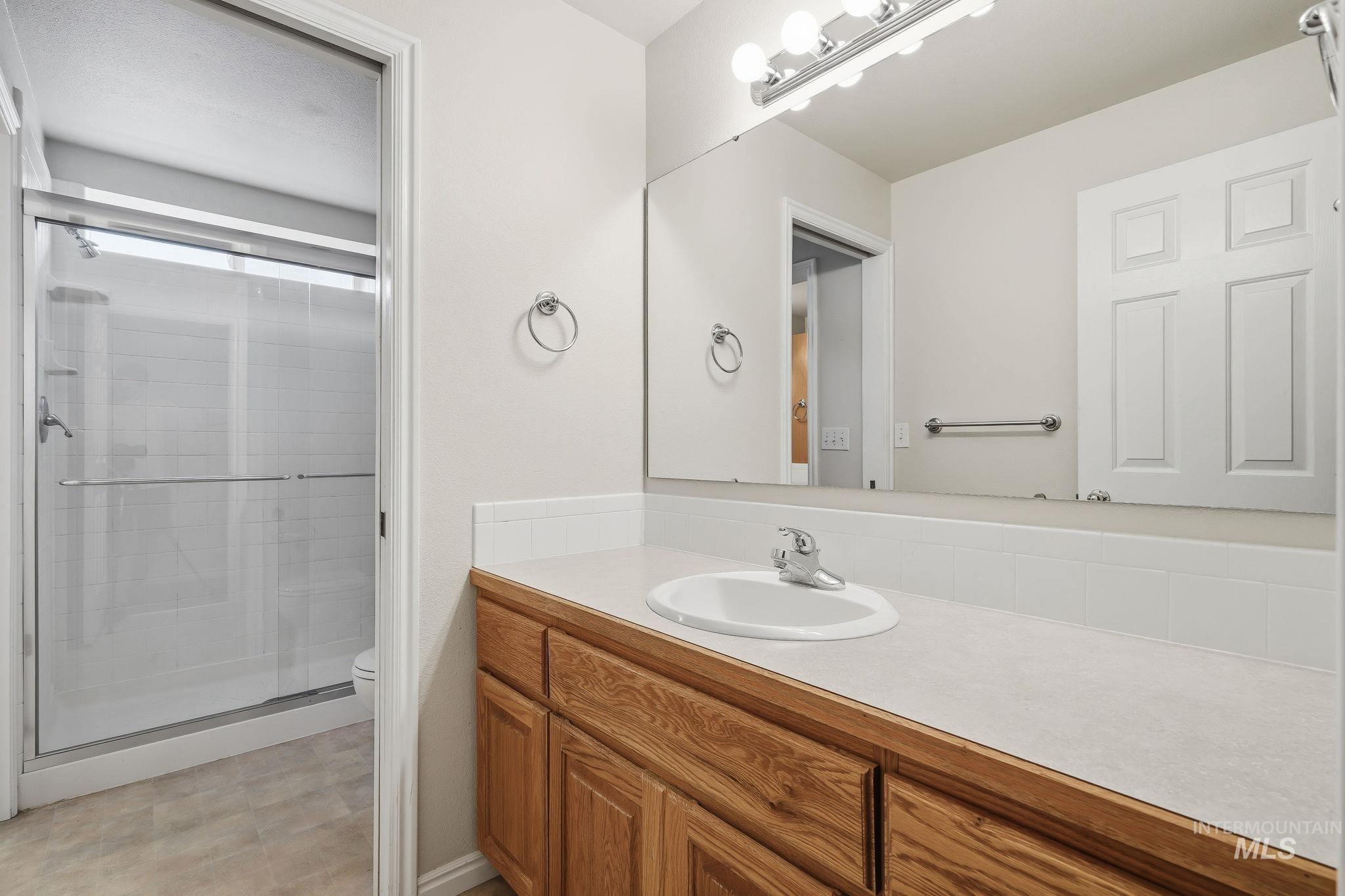 Bathroom vanity featuring a single basin sink, laminate countertop, and wood-finish cabinetry