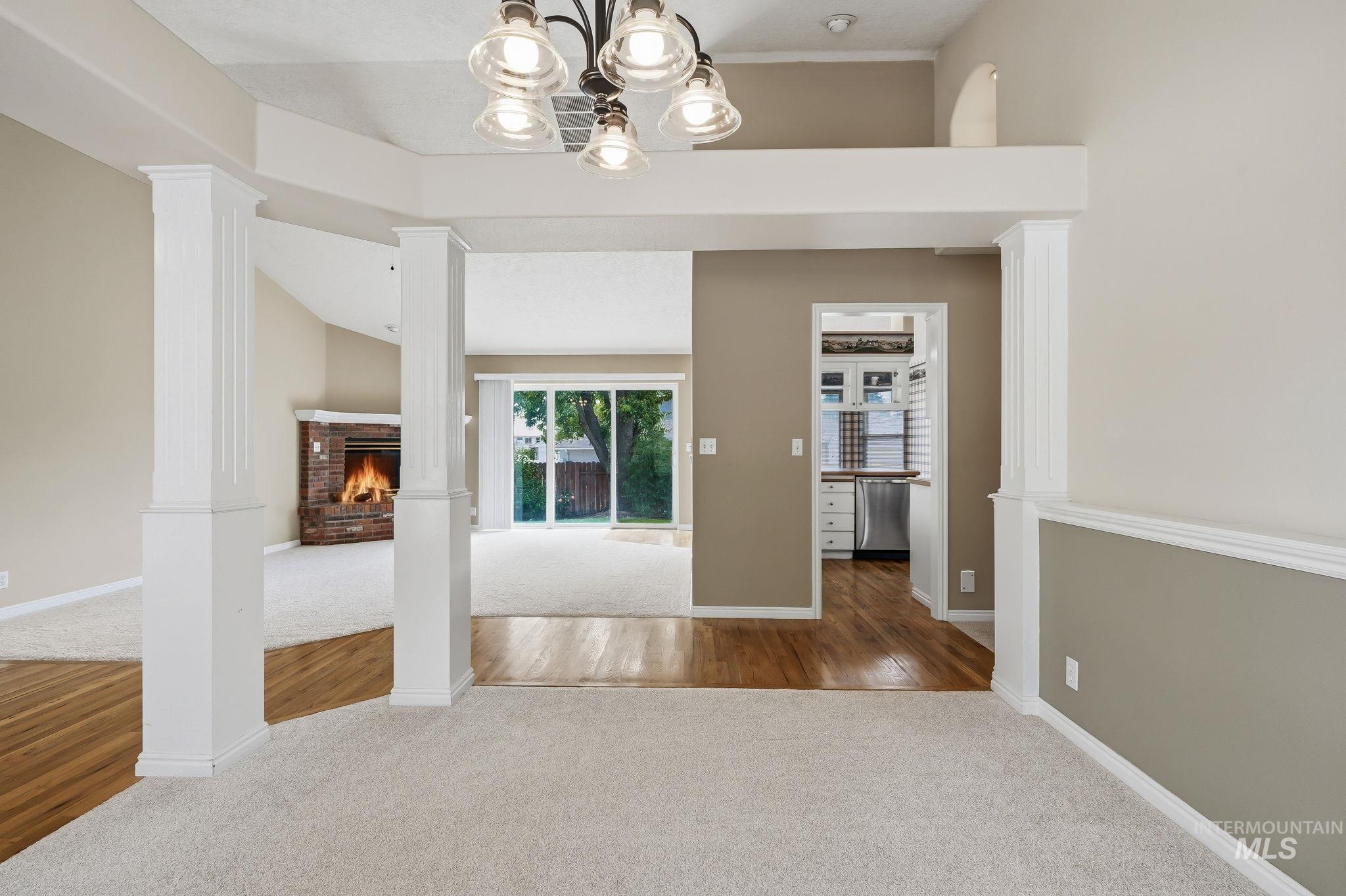 Interior space featuring white fluted columns, wood-finish flooring, and light-toned carpeting