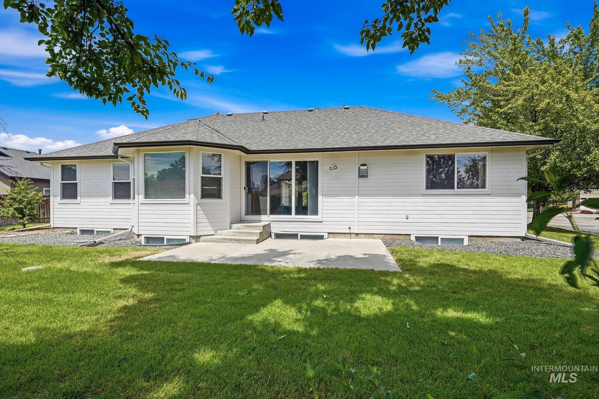 Rear exterior featuring white siding, a gray shingle roof, and a concrete patio