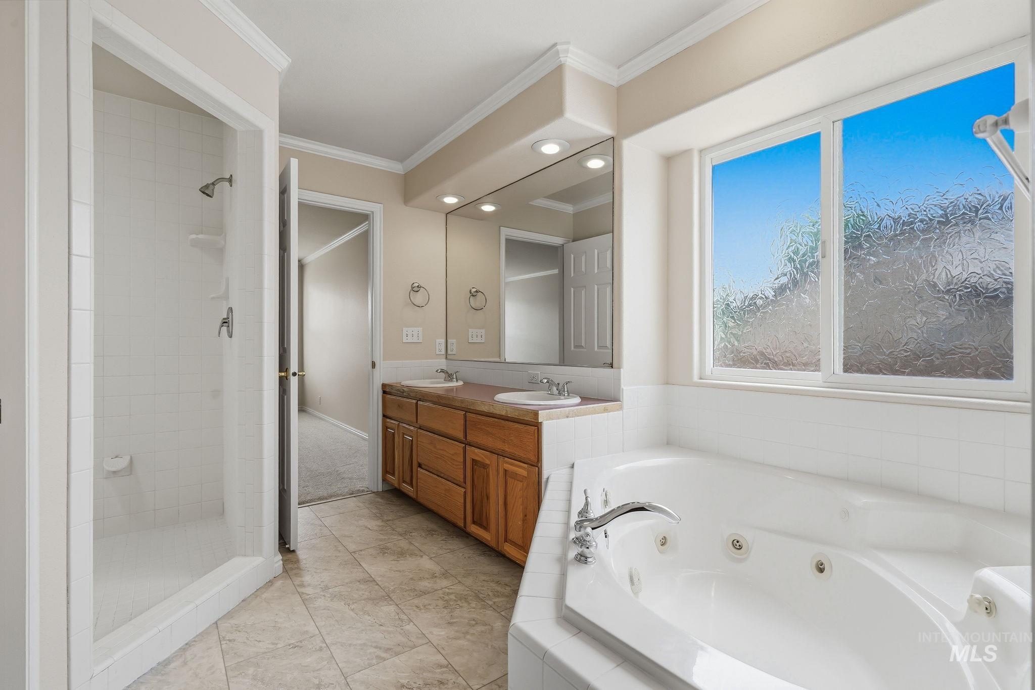 Contemporary bathroom featuring a corner jetted soaking tub, a separate shower enclosure with white tile, and a dual vanity with wood cabinetry and an integrated mirror