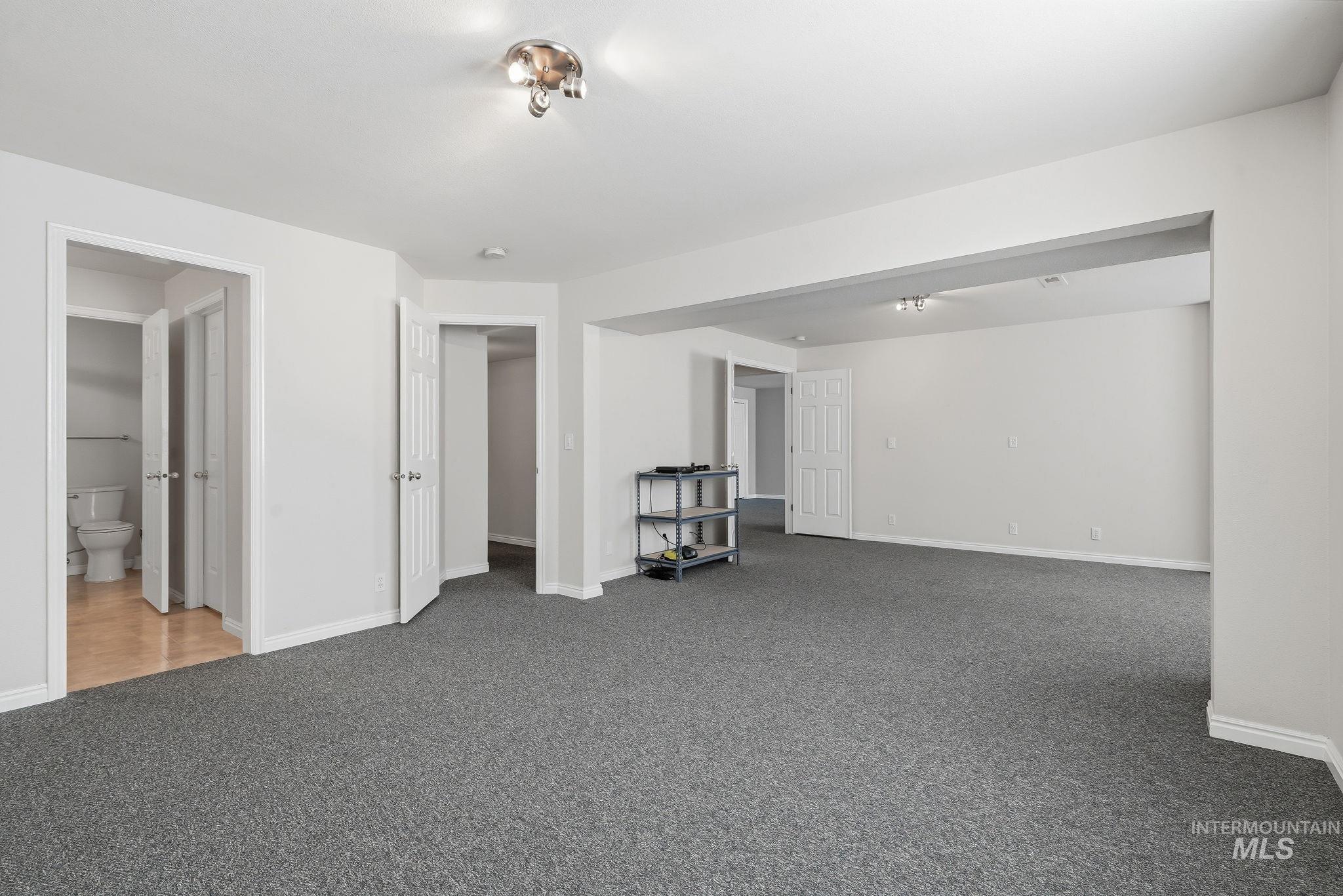 Expansive room featuring neutral-toned walls, gray carpeting, and white baseboards