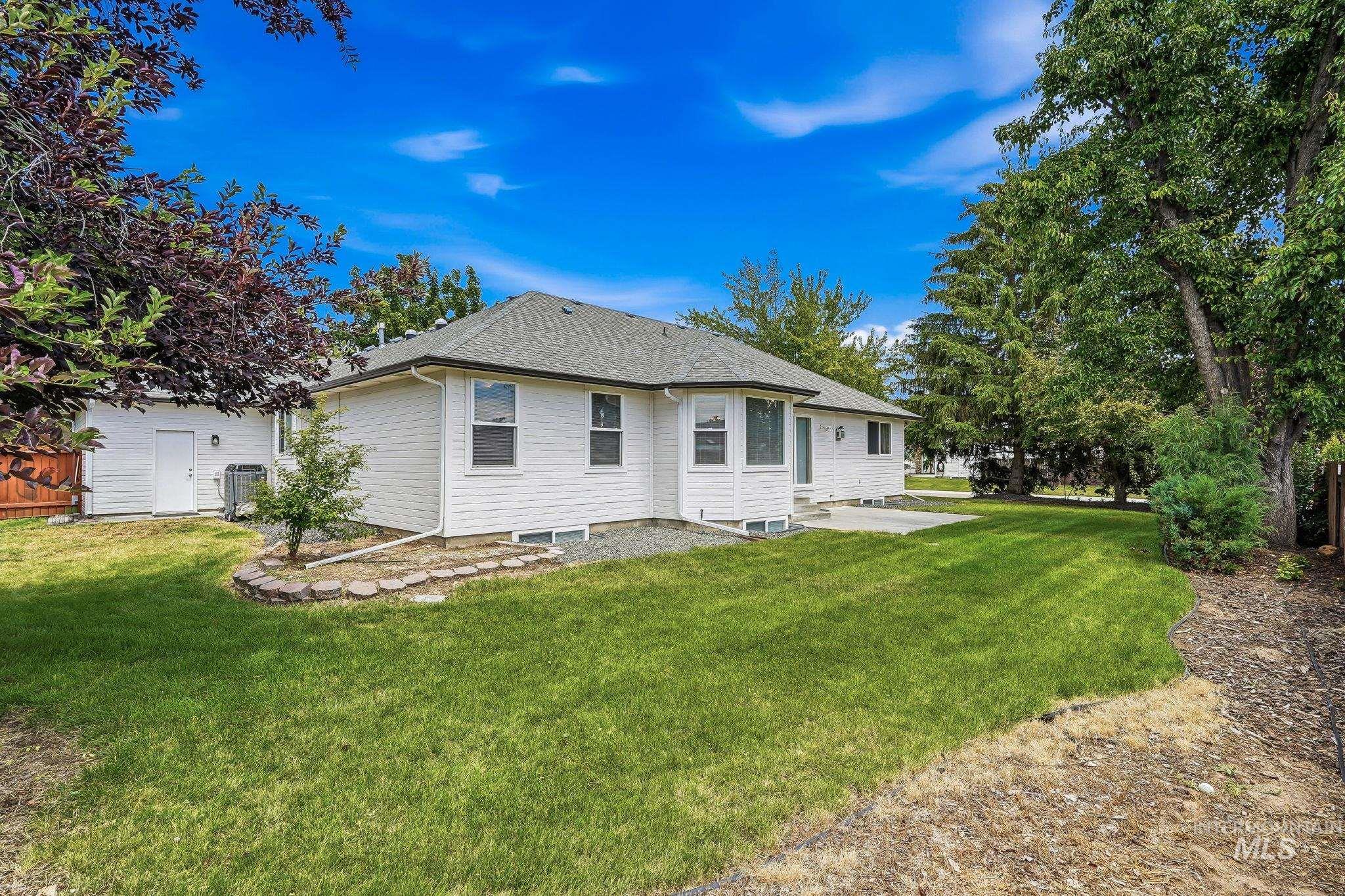 Expansive grassy yard with mature trees and a concrete patio