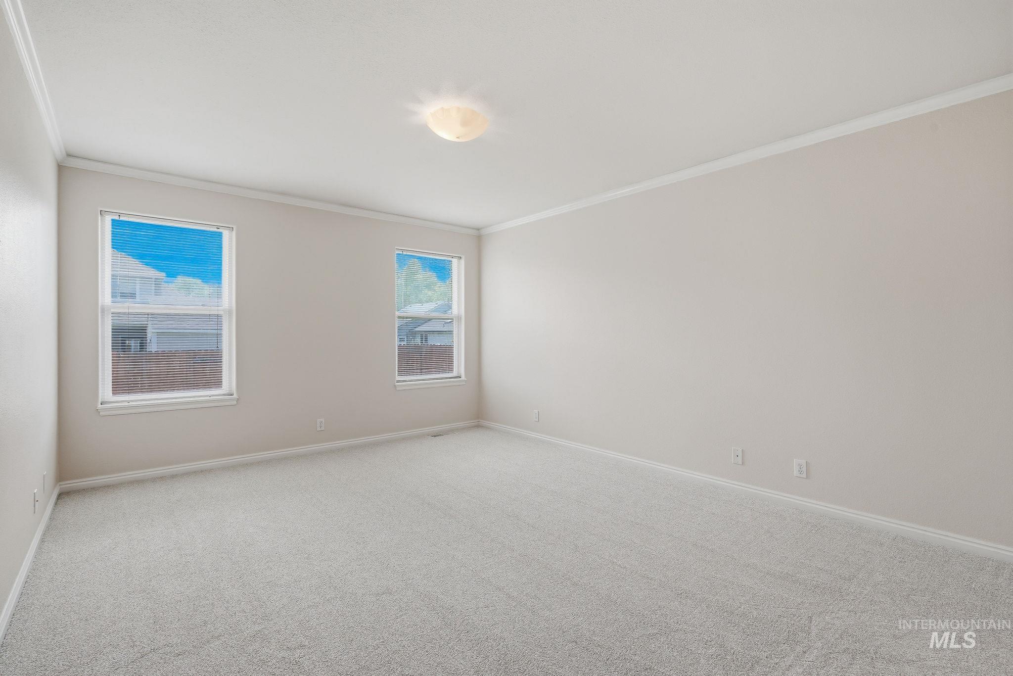 Spacious room featuring neutral paint, gray carpet flooring, white trim, and two double-hung windows